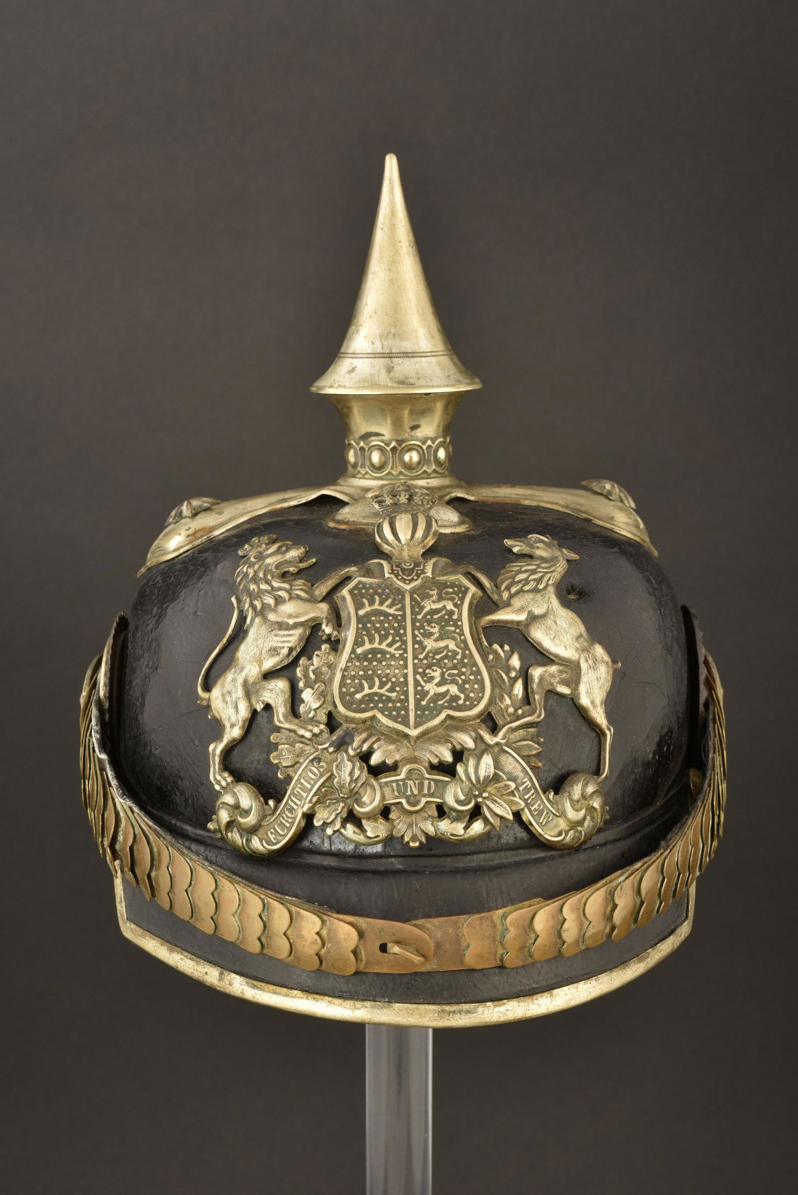 Casque a pointe d officier de Grenadier du Wurttemberg.: Casque a pointe a garnitures maillechort. Plaque aux armes du Wurttemberg, les bois du cerf manquant. Pointe devissable sur embase trefle avec Perlring, fixee par vis a tete en etoile, 2 sont des remp