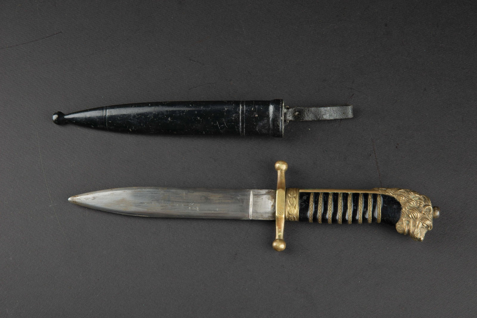 Dague marine italienne. Italian navy dagger.: Garniture en laiton. Pommeau Ã tete de lion. Poignee de couleur noir, filigrane or present. Garde complete. Lame complete dans sa longueur, usee et legerement affÃ»tee. Fabrication Scuotto Napoli