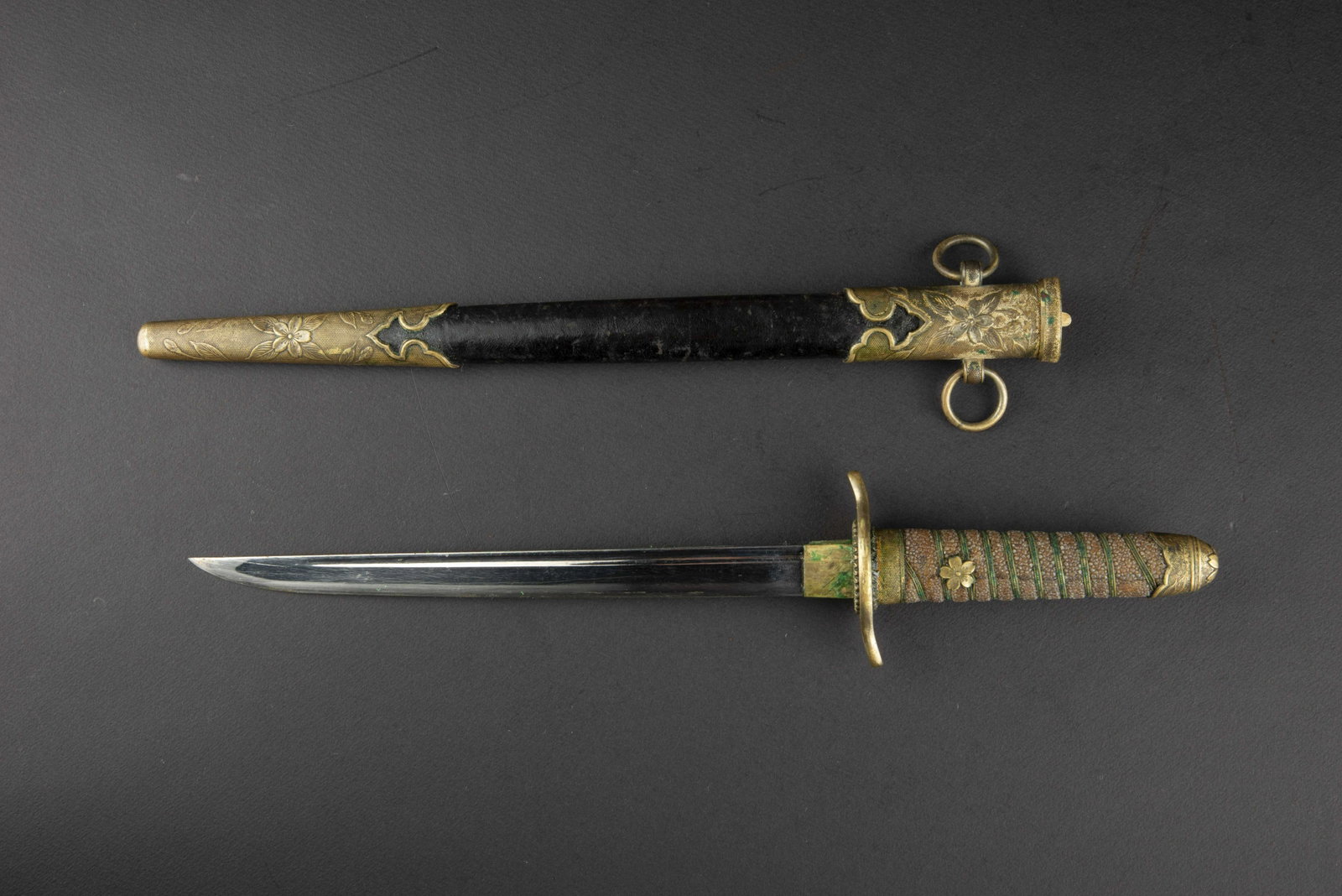 Dague officier japonais. Japanese officer dagger.: Poignee en galuchat, fendue. Filigrane present mais fortement oxyde. Pommeau et manche a decors de fleurs de cerisier. Garde en metal dore. Lame dans sa longueur d origine, sans marquages visibles. Fo