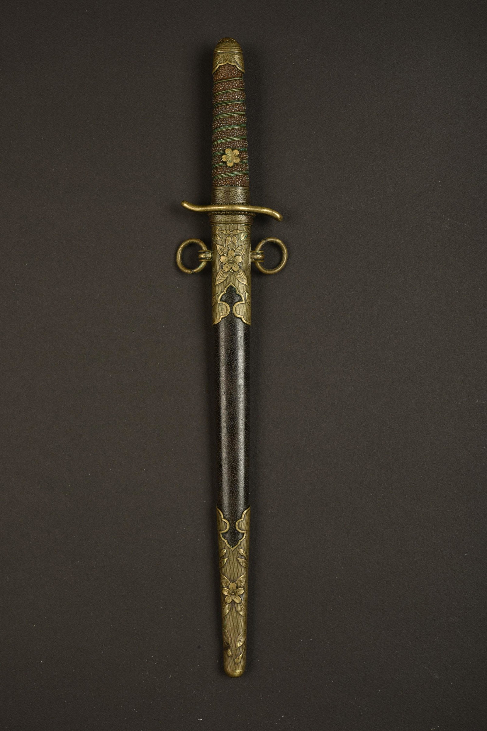Dague officier japonais. Japanese officer dagger.: Poignee en galuchat, fendue. Filigrane present mais fortement oxyde. Pommeau et manche a decors de fleurs de cerisier. Garde en metal dore. Lame fortement raccourcie et oxydee, sans marquages visibles