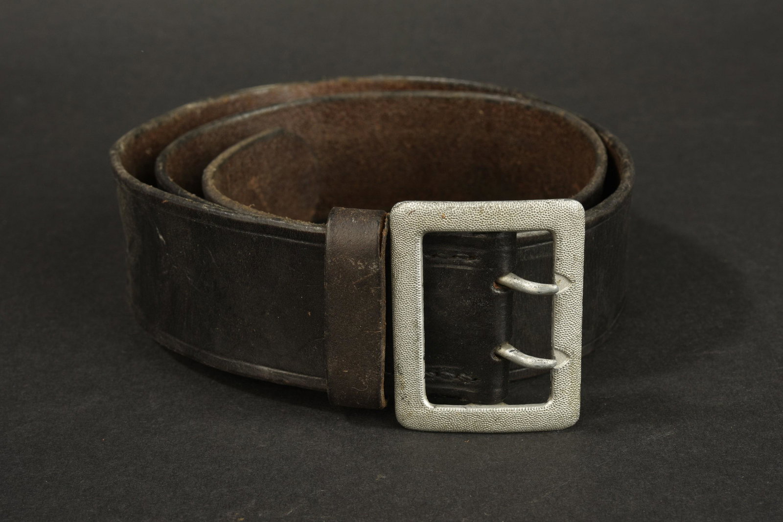 Ceinturon d officier allemand.: En cuir noir, boucle Ã deux ardillons en metal grenele argent. Sans marquages visible. Cuir graisse. A noter une certaine usure et patine de la piece. Provenance du Musee de la Seconde Guerre Mondi