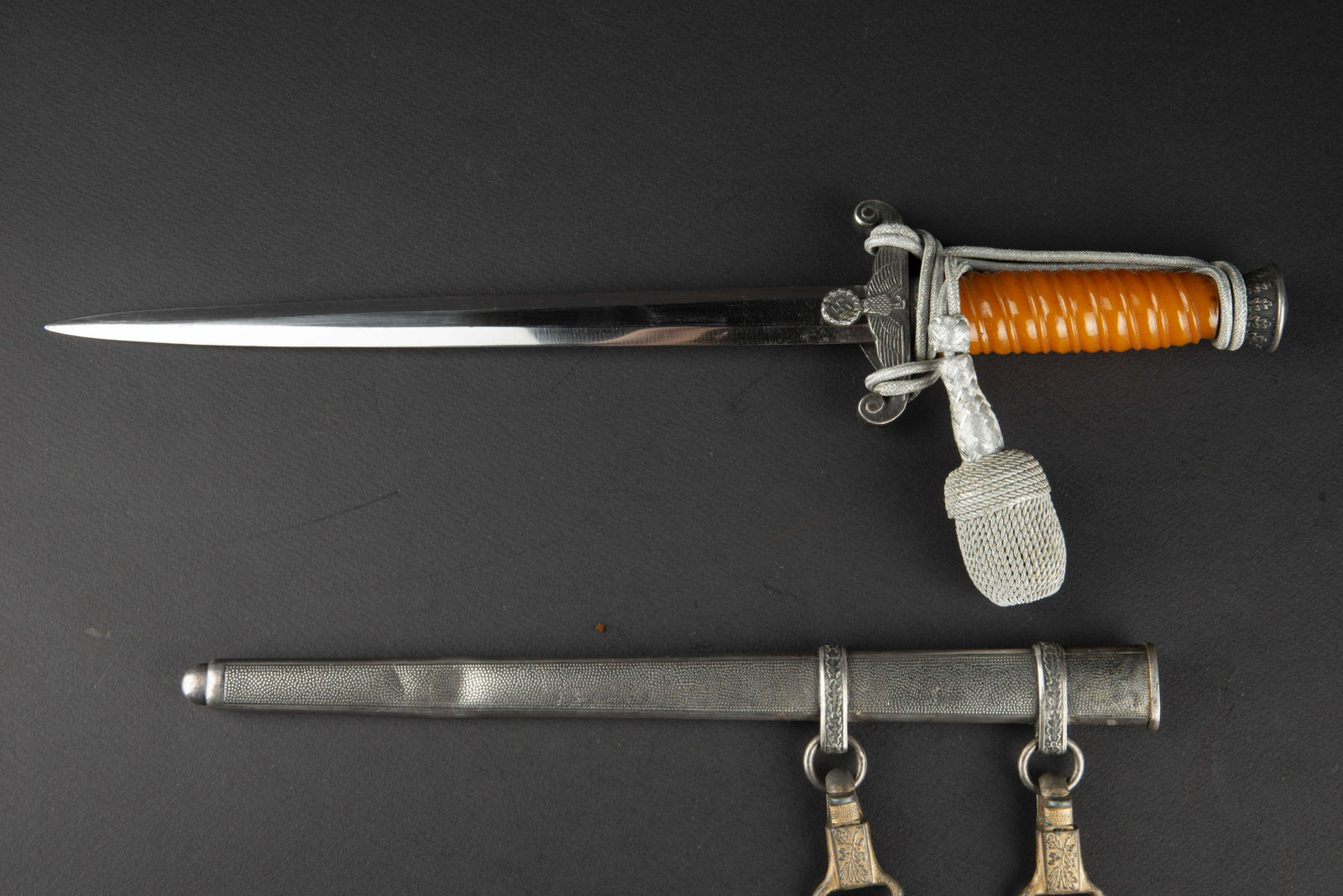 Dague d officier de la Heer. Heer officer dagger.: Garnitures en metal, couleur argent. Fusee de couleur orange. Dragonne en fil d argent monte de maniere reglementaire. Fourreau en metal grenele, bagues decorees de feuilles de chene. Bossele sur sa d