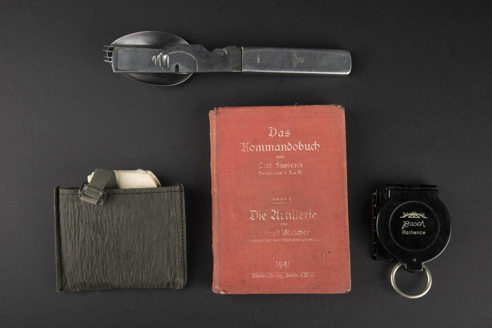 Ensemble d equipement. Equipment set.: Comprenant une boussole en bakelite noir, fonctionnelle, cadran marque DRGM, miroir present. Anneau en metal complet, couvercle marque Busch Rathenow. Un couvert individuel, complet, fourchette cuille