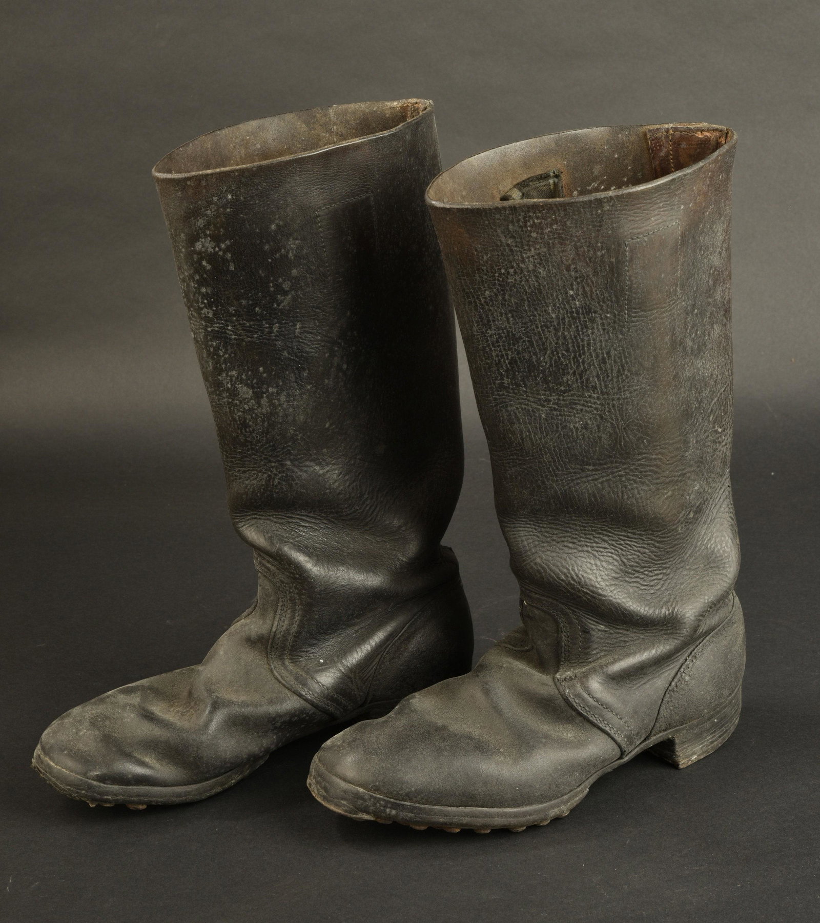 Bottes allemande. German boots.: Paire homogene en cuir noir, tiges hautes. Semelles cloutees et ferrees. Marquages 27 1 2 14 72 M 381 1557 8. Quelques manques au niveau de la semelles. Un trou a ete perce sous la semelle pour permet
