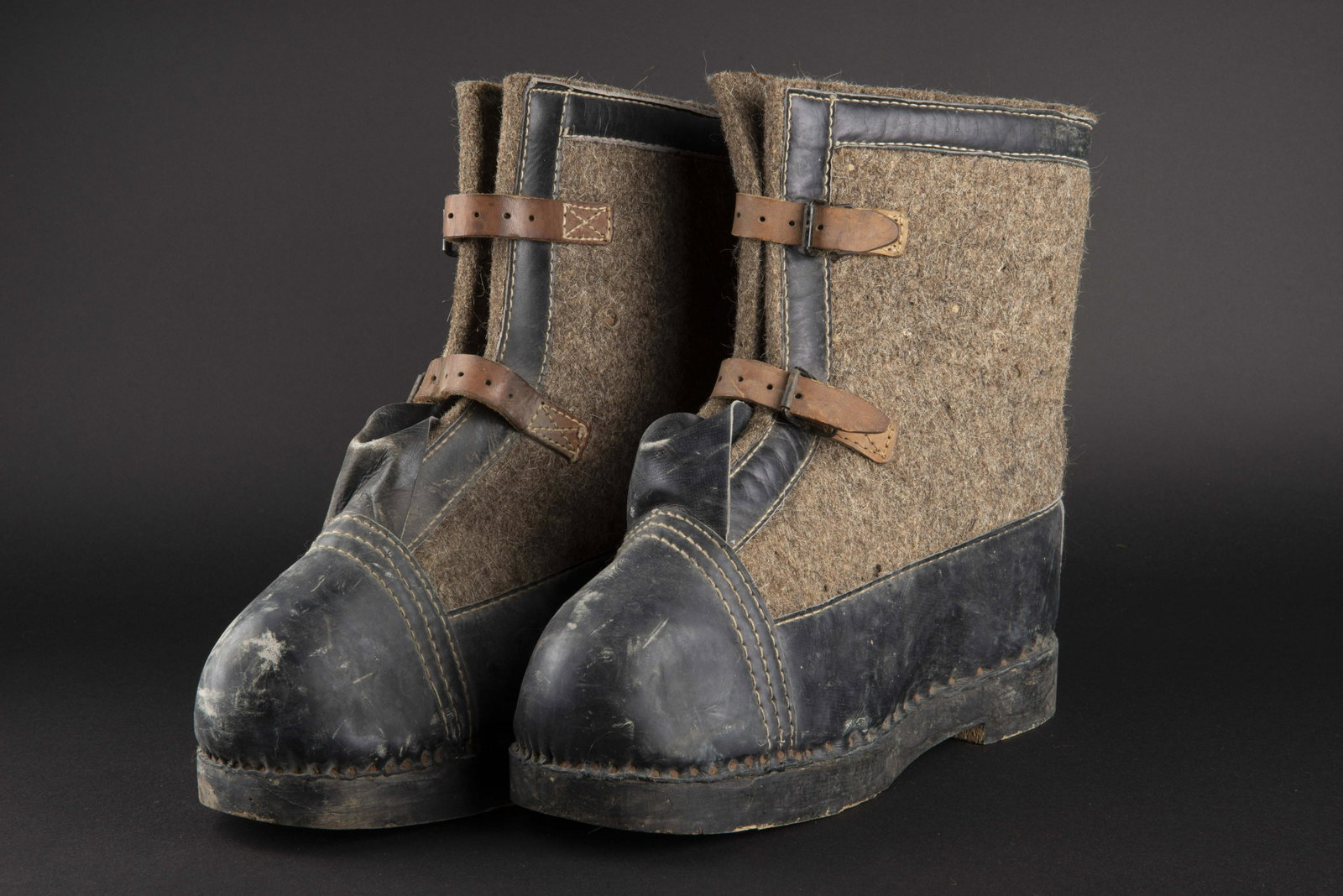 Bottes de garde. Guard boots.: En feutrine et cuir noir. Languettes completes, les sangles de fermeture sont presentes. Semelles en bois. Etiquette marquee Herm Muller Hartha I SA 1943, taille 34. Paire homogene. A noter une certai