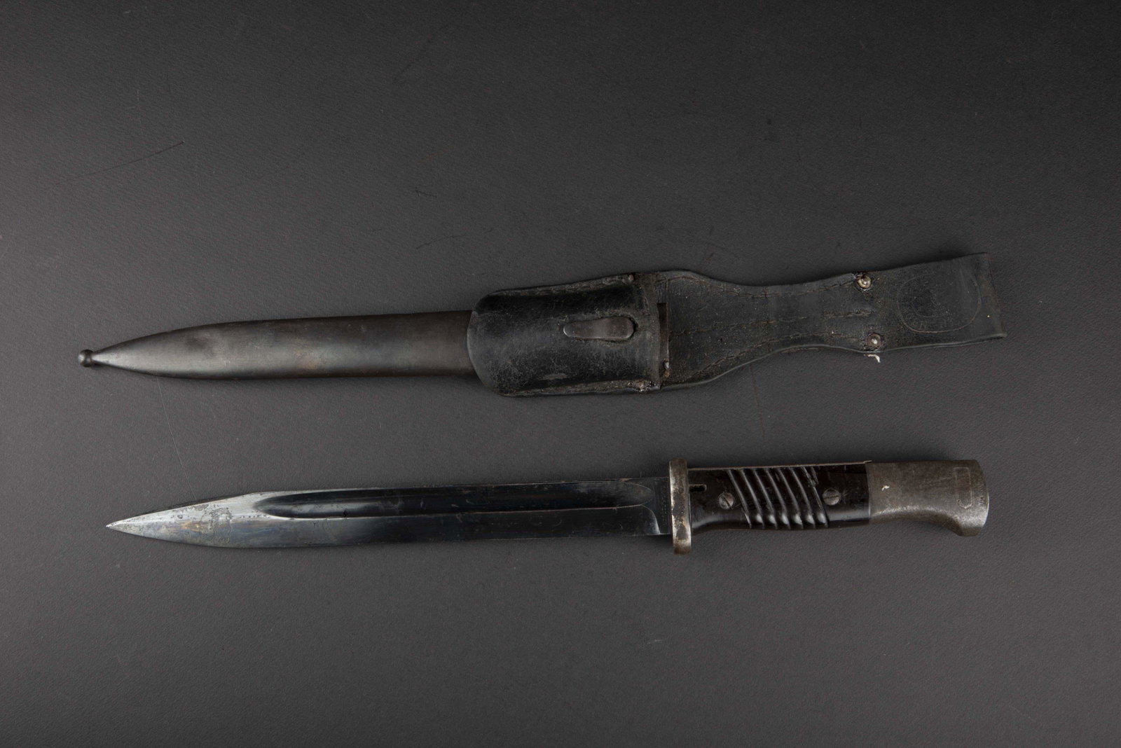 Baionnette 98K. 98K bayonet.: Plaquettes en bakelite noire, presentant des marques de griffures. Garnitures en metal, dans sa couleur d origine, Ã 45%. Lame dans sa couleur d origine Ã 70%, quelques marques d usure et d oxyd