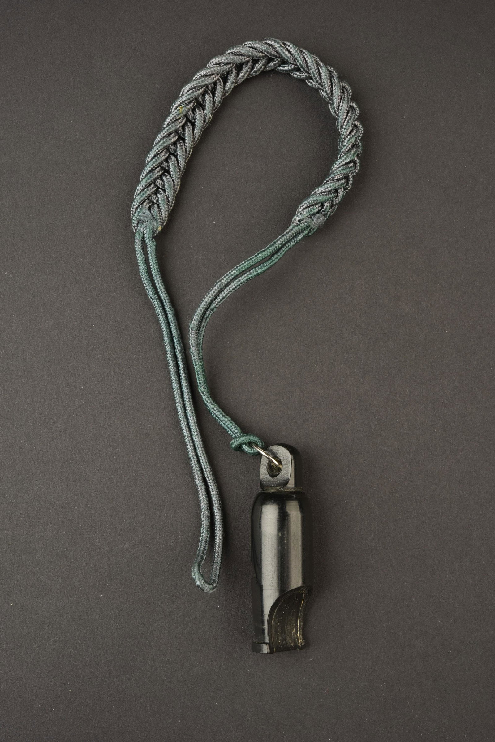 Sifflet allemand. German whistle.: En bakelite noire, fonctionnel. Sans marquages visibles. Cordon tresse vert complet. A noter une certaine usure et patine de la piece. Plus de photos sur aiolfi.com. In black bakelite, functional. Wit