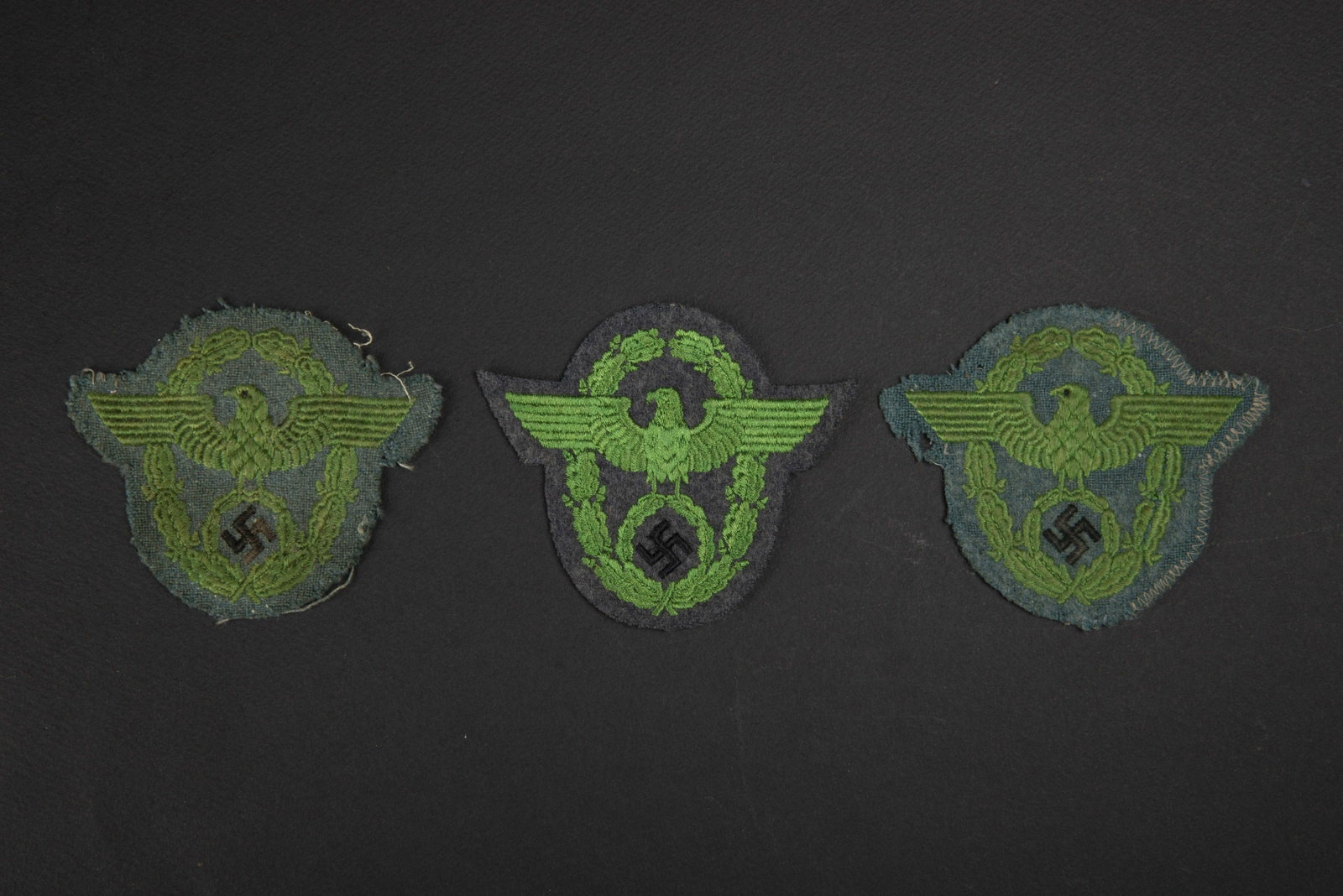 Aigle de bras Polizei. Polizei arm eagle.: Comprenant un aigle de bras en brode en fil vert, sur fond en drap gris vert, demonte d une vareuse. Un aigle de bras en fils vert sur fond en drap gris vert. Un aigle de bras en fil vert sur fond en 