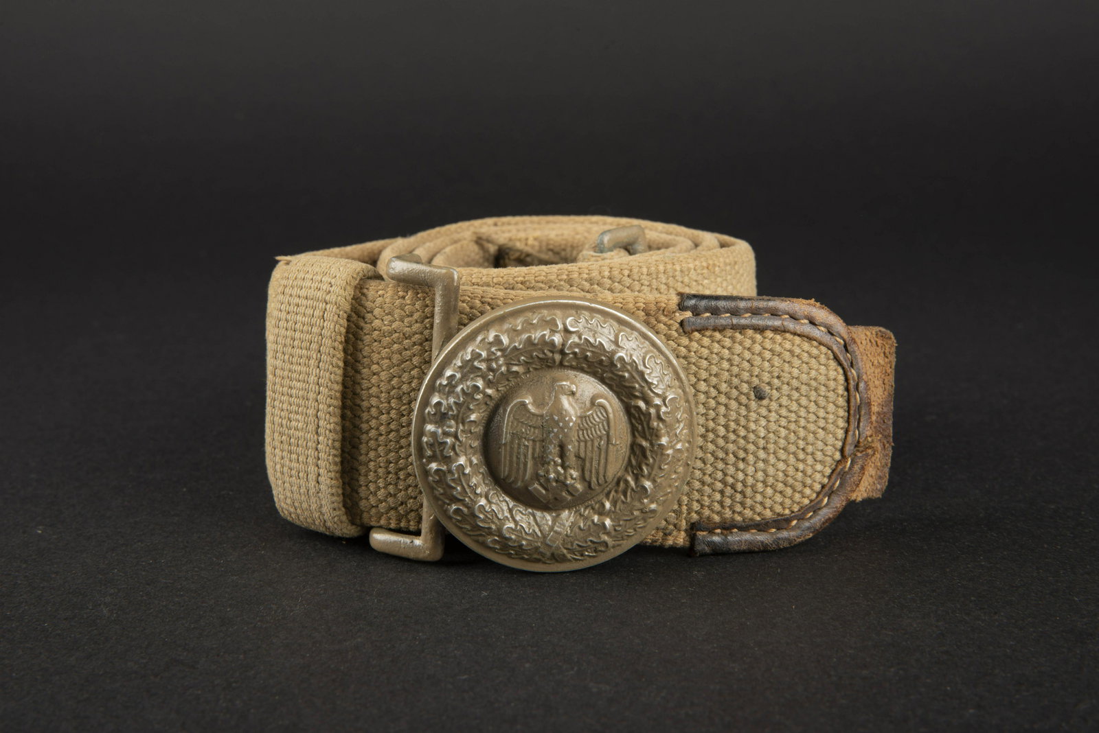 Ceinturon officier AK. AK officer belt.: Ceinturon en forte toile, sable. Bouclerie en aluminium peint, a 80%. Taille 110. Patte de reglage en cuir marron. Les deux passants en toile sont presents. Fabrication G Reinhardt Berlin 1941. Boucle