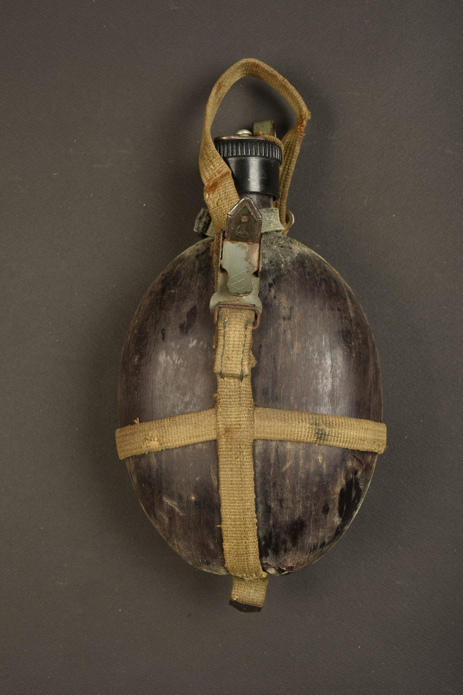 Gourde AK. Afrikakorps canteen.: Gourde coco. Datee 1942. Bouchon en bakelite present. Modele sans housse. Harnais en toile, les parties metalliques sont oxydees. Mousqueton complet. A noter une certaine usure et patine de la piece. 
