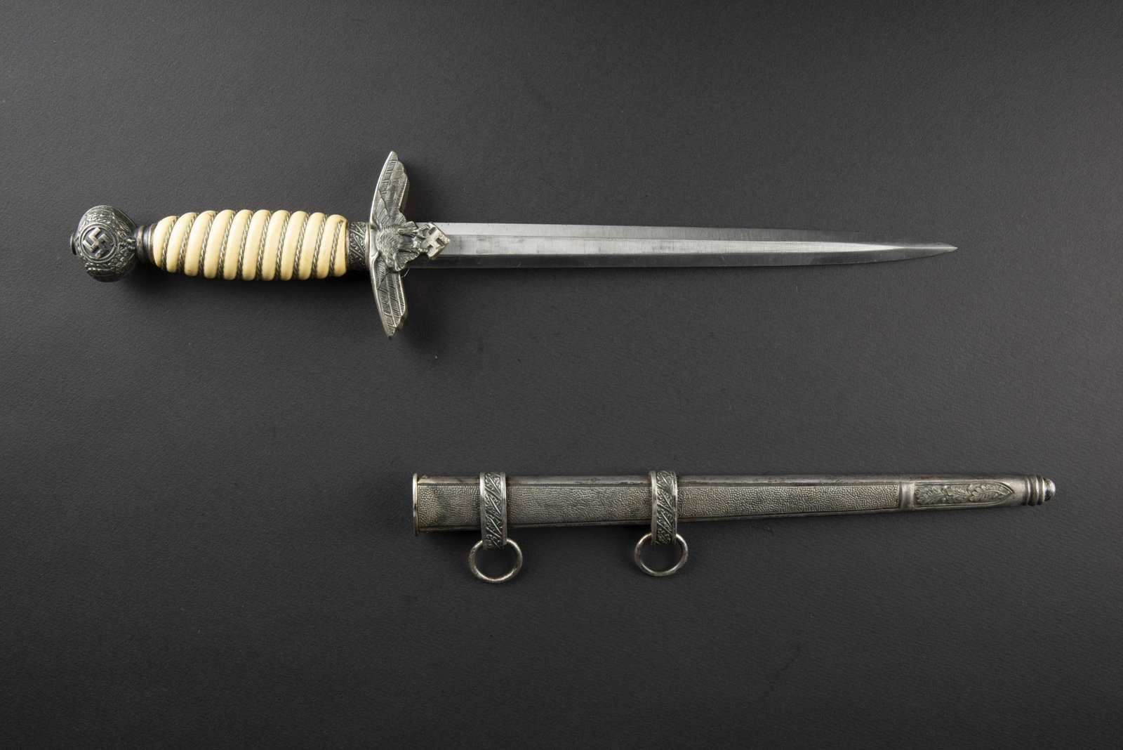 Dague officier Luftwaffe. Luftwaffe dagger.: Garnitures en metal couleur argent. La dorure des insignes nationaux est manquante. Poignee de couleur blanche, lisere argent. Lame en tres bel etat. Fabrication Paul Weyersberg Solingen. Fourreau en 
