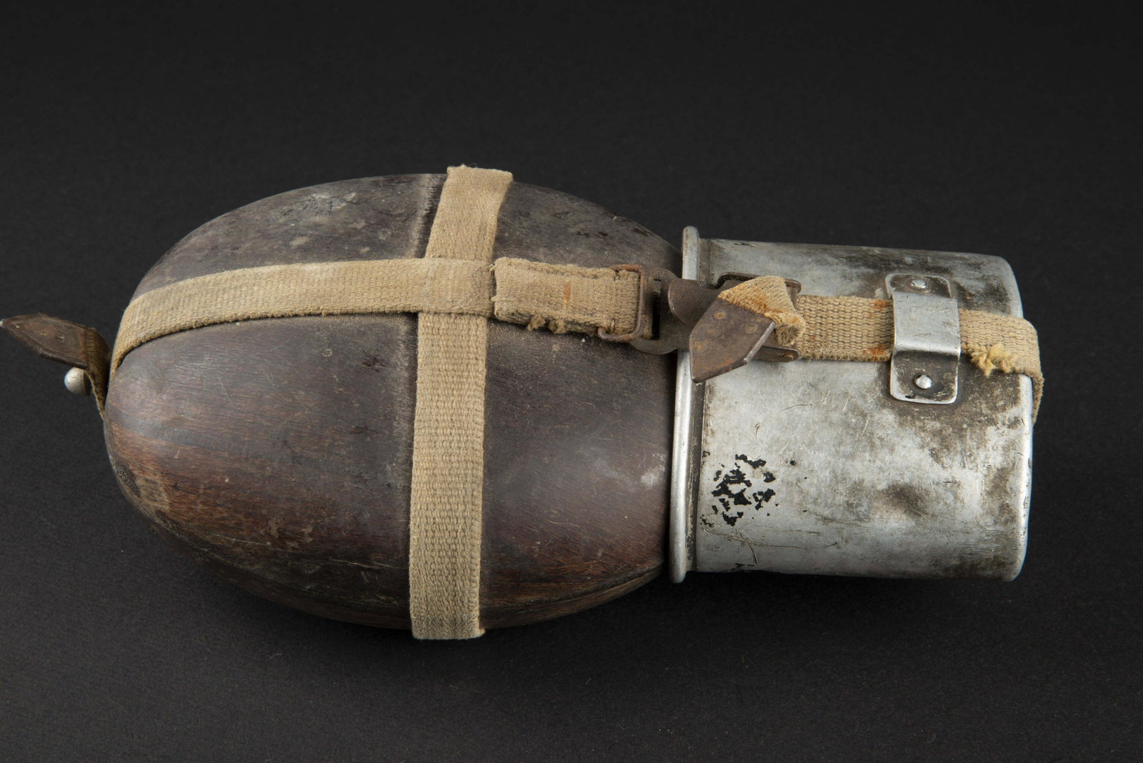 Gourde allemande. German canteen.: Gourde type coco, usee. Fabrication datee 1942. Bouchon en bakelite present. Harnais en toile, complet, bouclerie marquee LUX. Mousqueton complet. Quart en aluminium, peinture quasi manquante. Fabrica
