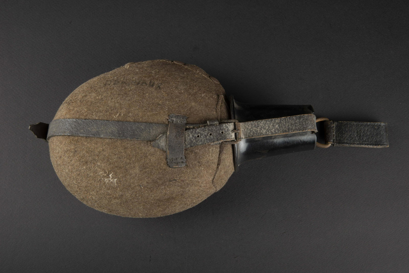 Gourde allemande. German canteen.: Grande contenance, en aluminium. Housse en feutre, renfort au dos. Harnais en cuir complet, mousqueton fonctionnel. Un passant de ceinturon present, sans marquages visibles. Quart en bakelite. Reste d