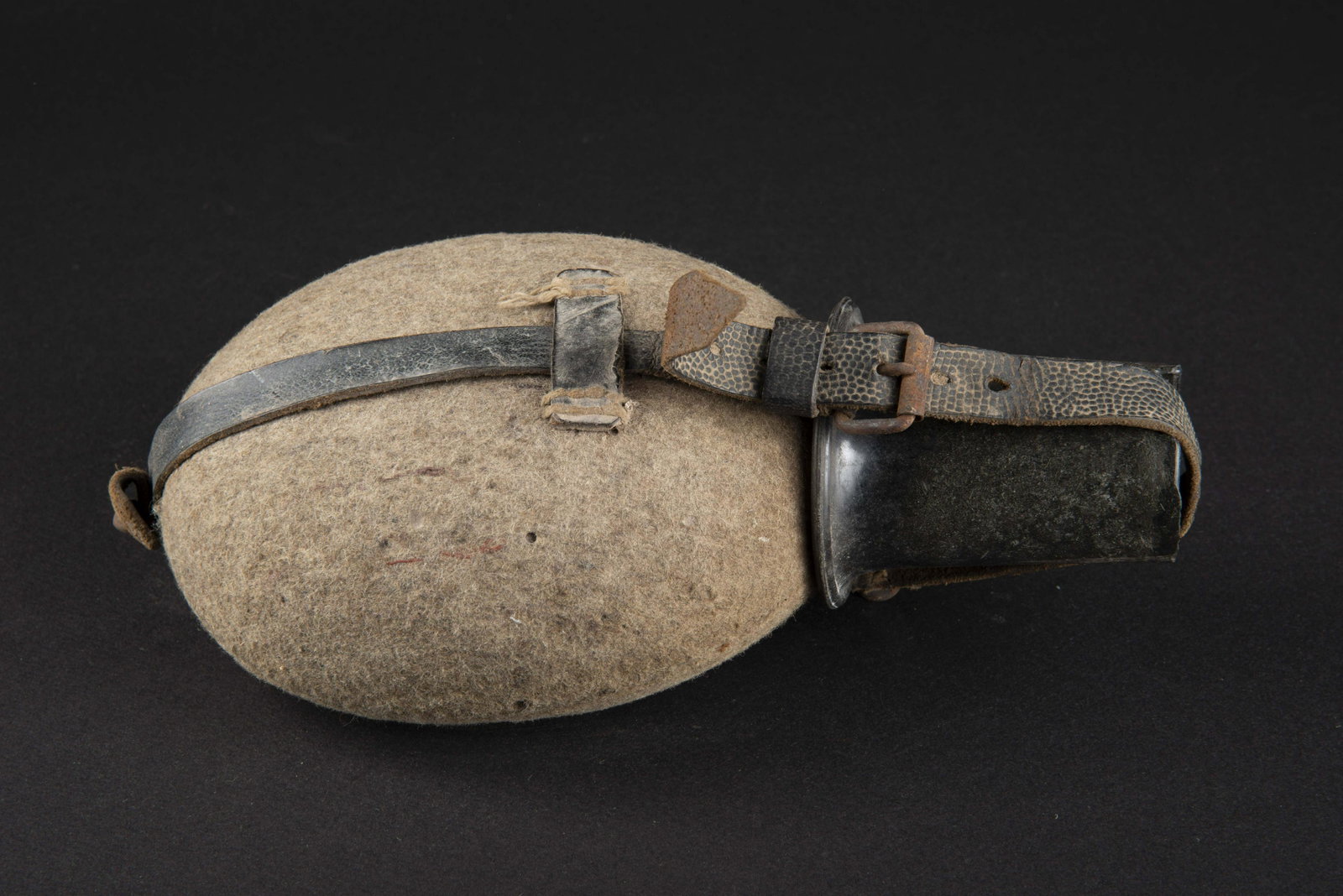 Gourde allemande. German canteen.: Gourde en aluminium. Housse en feutrine kaki, tous les boutons pressions sont fonctionnels. Quart en bakelite. Harnais en cuir present, cuir craquele et fragilise. Mousqueton complet. A noter une cert