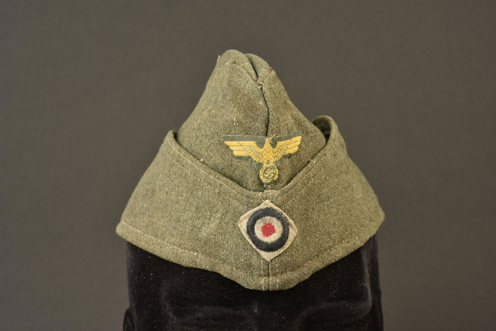 Calot artillerie cÃ´tiere. Coastal artillery cap.: En drap Feldgrau. Aigle Bevo typique des unites de l artillerie cÃ´tiere. Cocarde Bevo sur fond gris. Les insignes sont montes main. Interieur double en tissu vert, marquage 38349. Piece decoloree p