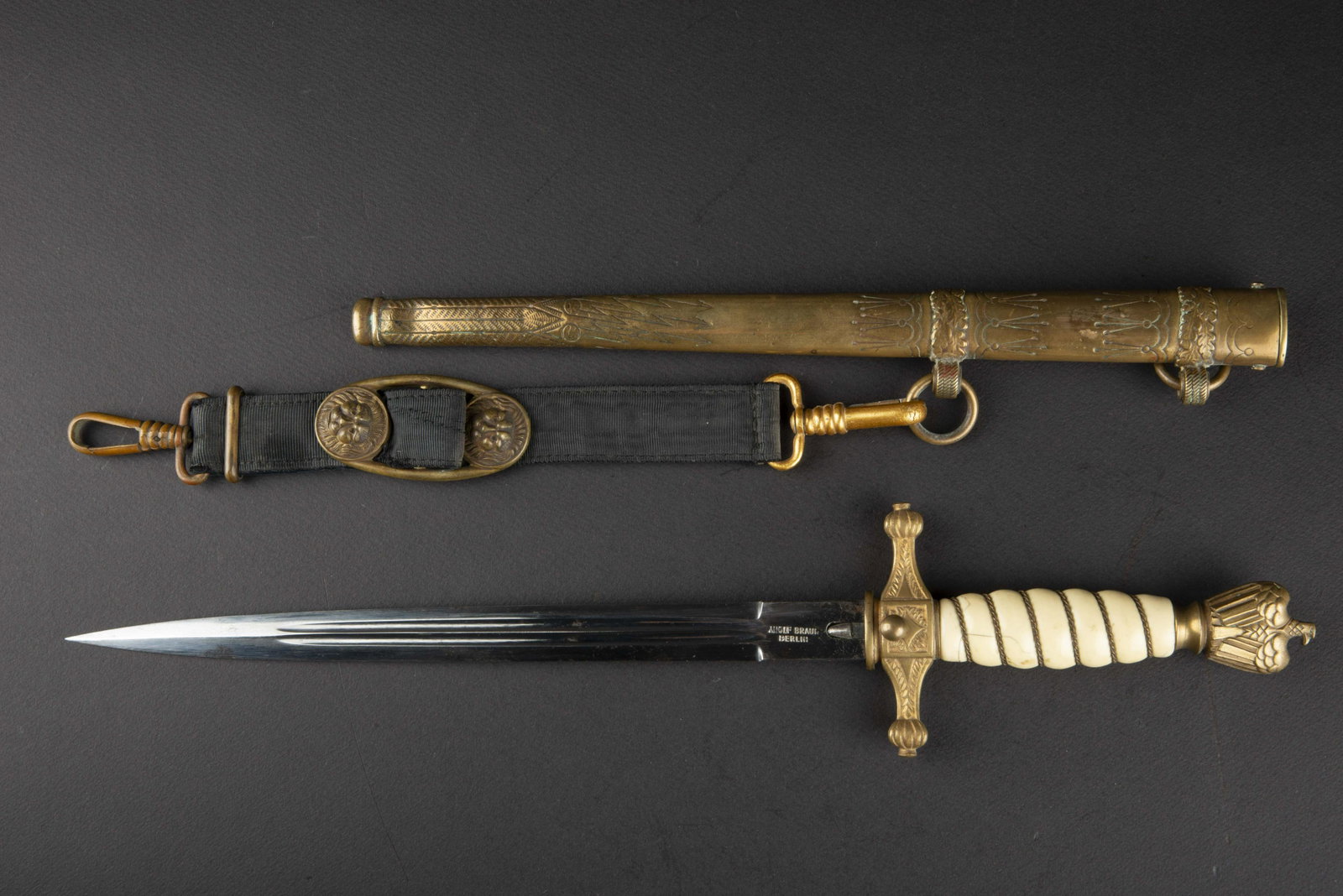 Dague d officier KM. Kriegsmarine officer dagger.: Garnitures en metal dore. Fusee de couleur blanche presentant quelques taches, fissures et manques, filigrane present. Dragonne absente. Fourreau martele, presentant quelques bosses, bagues decorees d