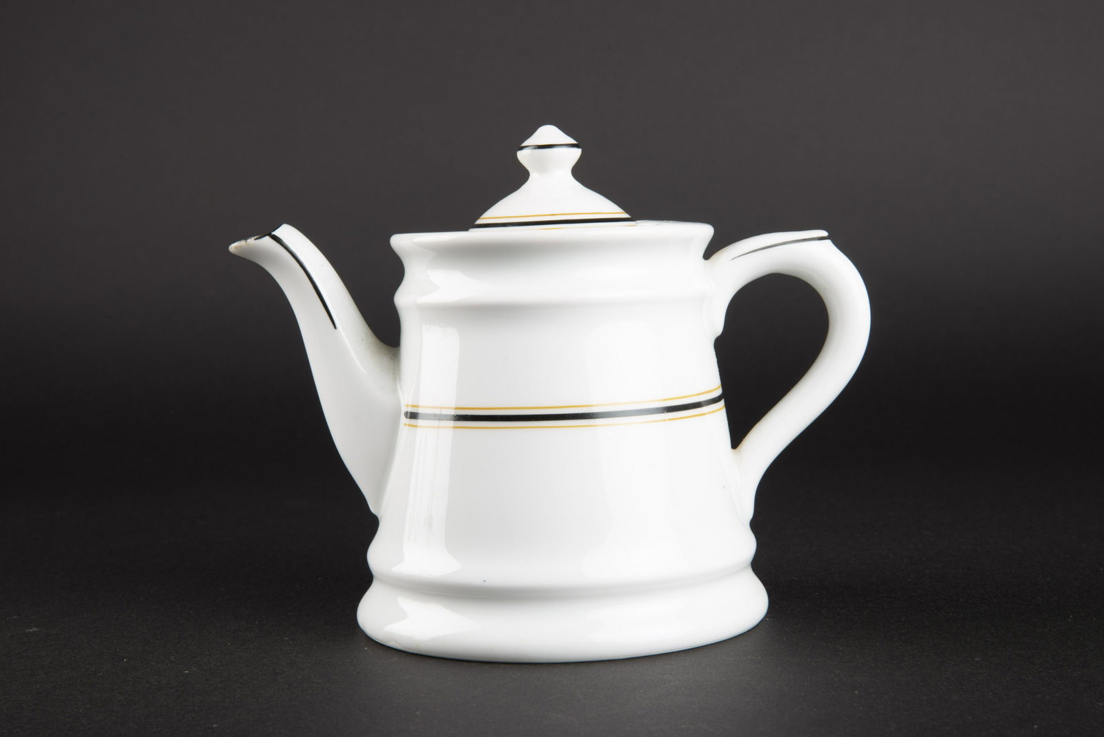 Theiere KM. Kriegsmarin teapot.: En porcelaine blanche, couvercle complet. Anse presente, bec verseur complet. Double lisere noir et or. Ce lisere correspond au mess des officiers superieurs. Fabrication Koenigszelt 1921. A noter une