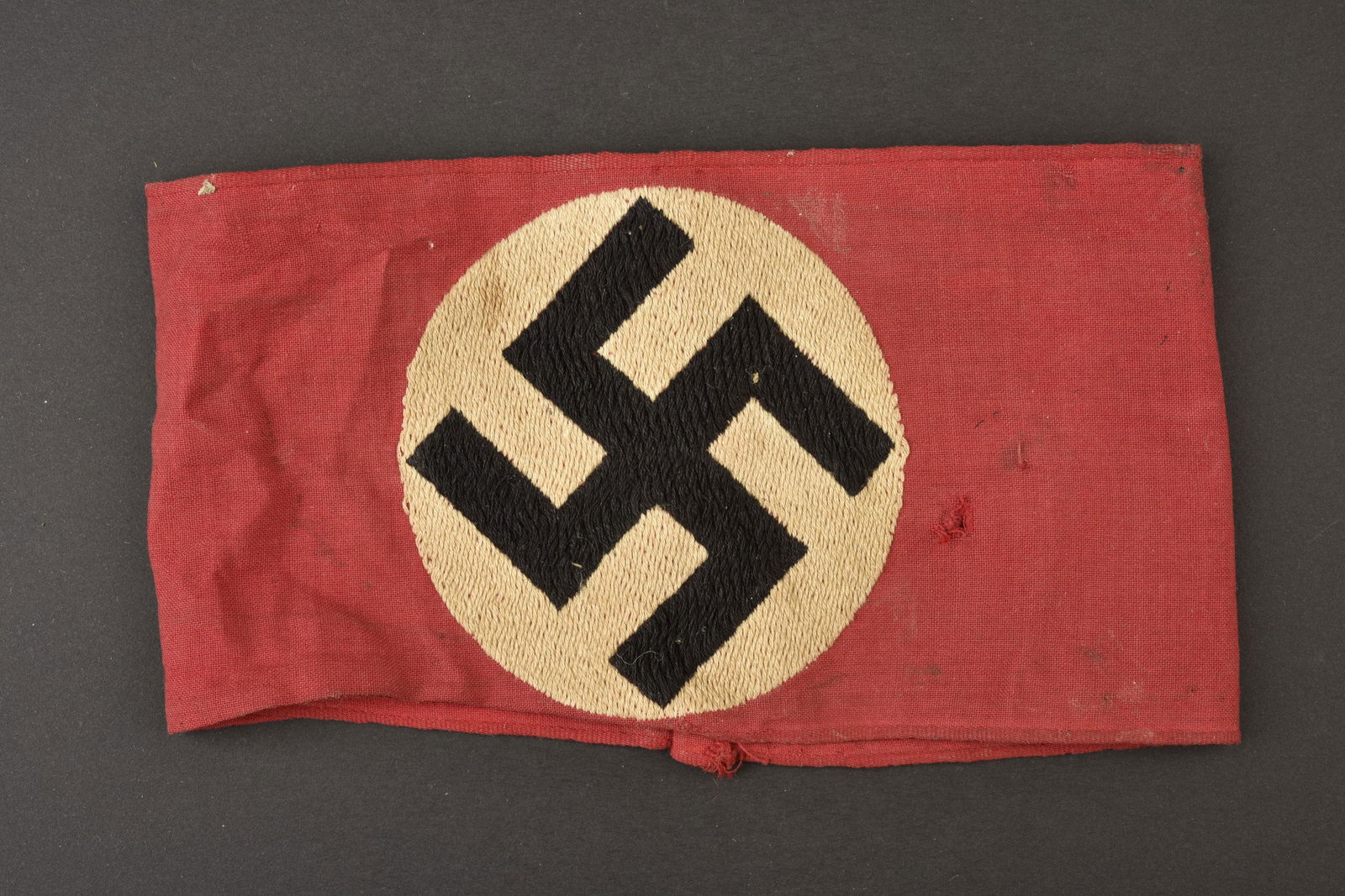 Brassard allemand. German armband.: En tissu coton rouge, insigne national brode directement sur le b brassard, sans marquage visible. A noter une certaine de la piece ainsi que de nombreuses taches. Plus de photos sur www.aiolfi.com. I