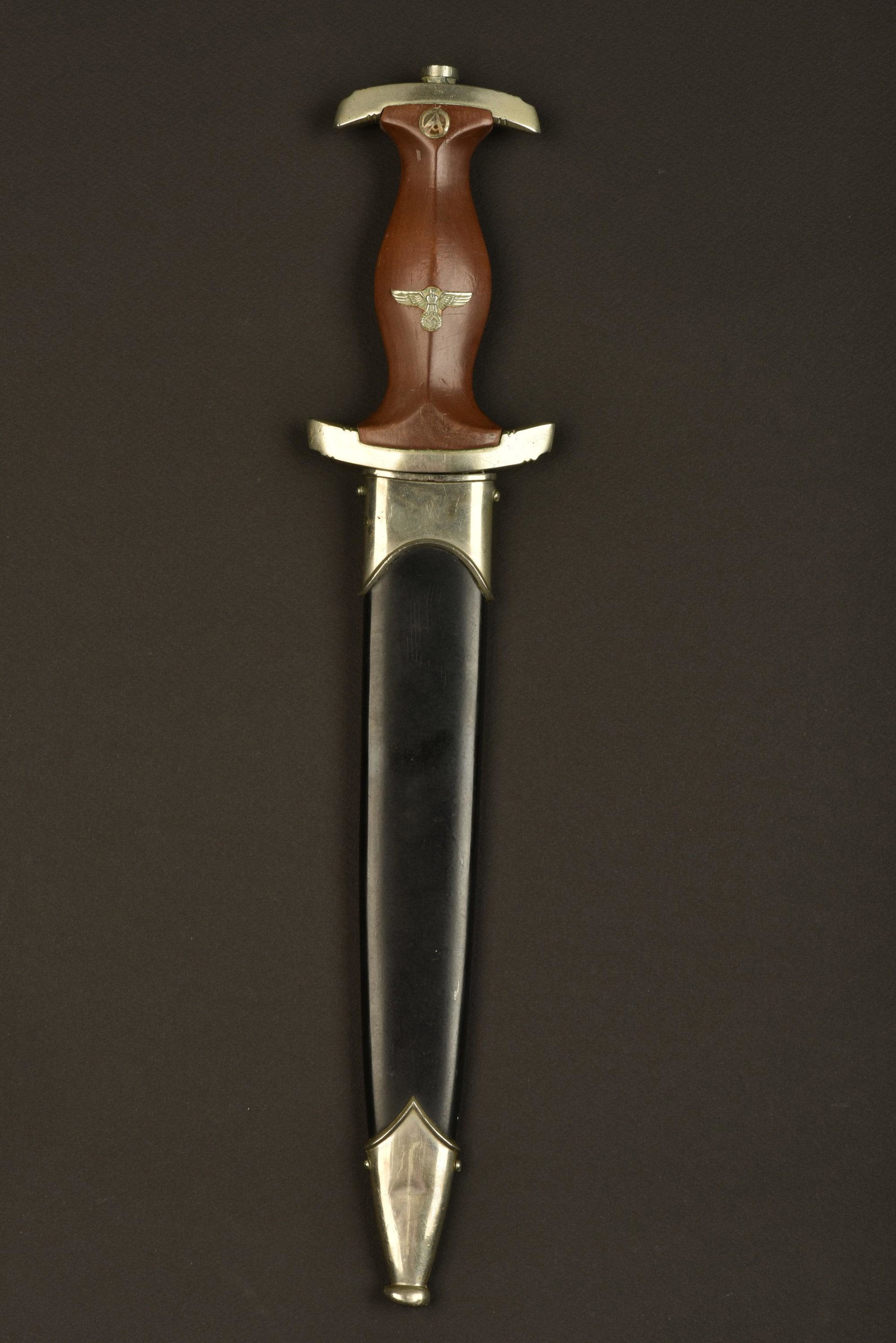 Dague NSKK. NSKK dagger.: Garnitures en metal couleur argent. Poignee en bois, insigne SA et aigle allemand montes d origine. Garde marquee du NSKK Gruppe Marches du nord. Quelques marques au niveau du manche en bois. Lame com