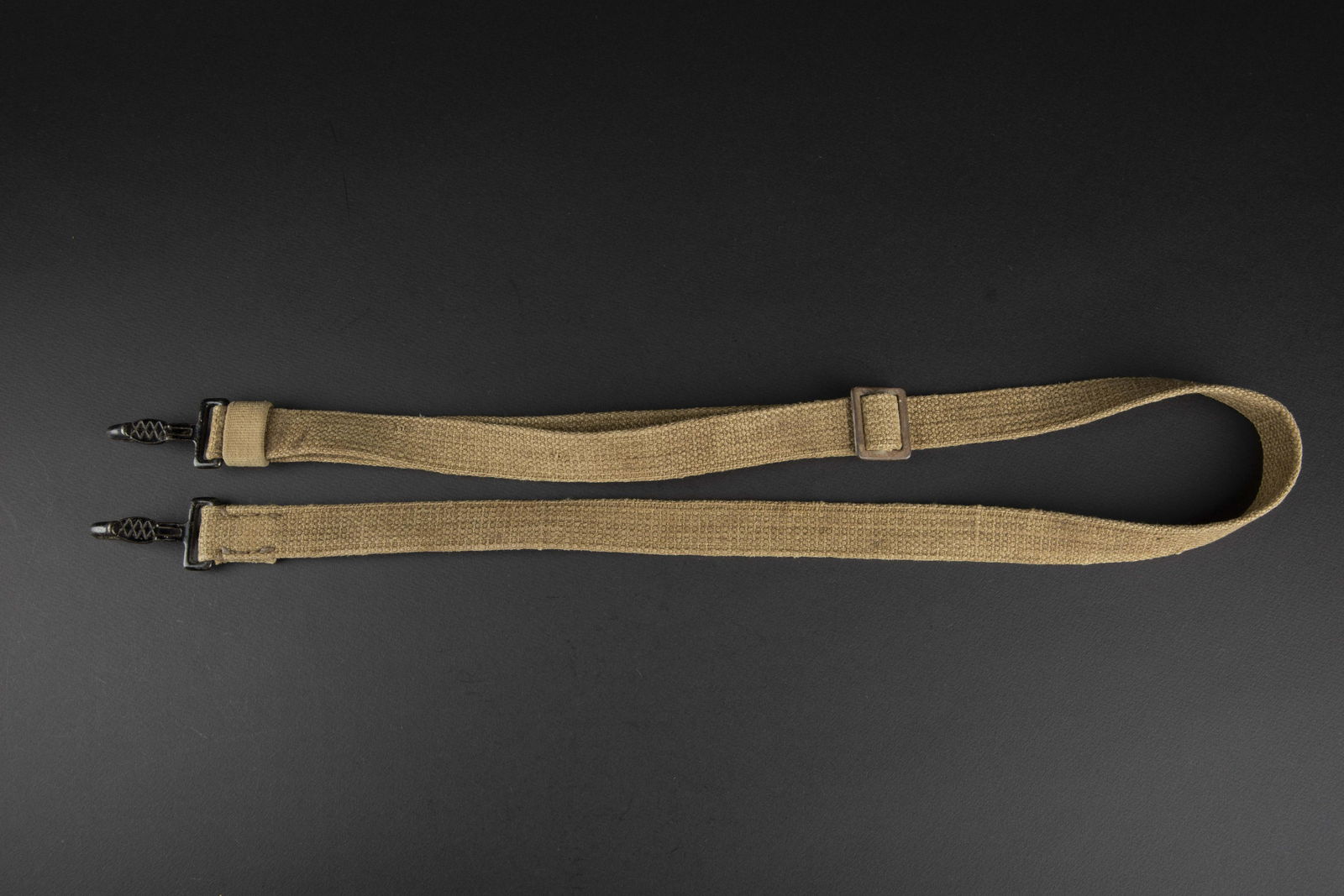 Sangle pour optique allemande. Strap for German optics.: Sangle pour optique allemande. En forte toile sable. Les mousquetons sont complets et en couleur d origine noir. Sans marquages visibles. A noter une certaine usure et patine de la piece. Etat II+. St