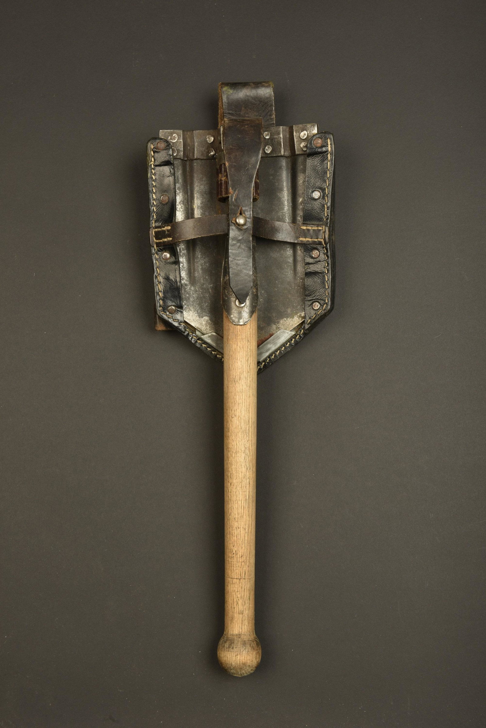 Pelle allemande. German shovel.: Pelle allemande. Pelle pliante, partie metallique disposant d un logo fabricant. Partie mobile fonctionnelle. Manche en bois use et nettoye. Housse en epais cuir noir, toutes les sangles sont presente