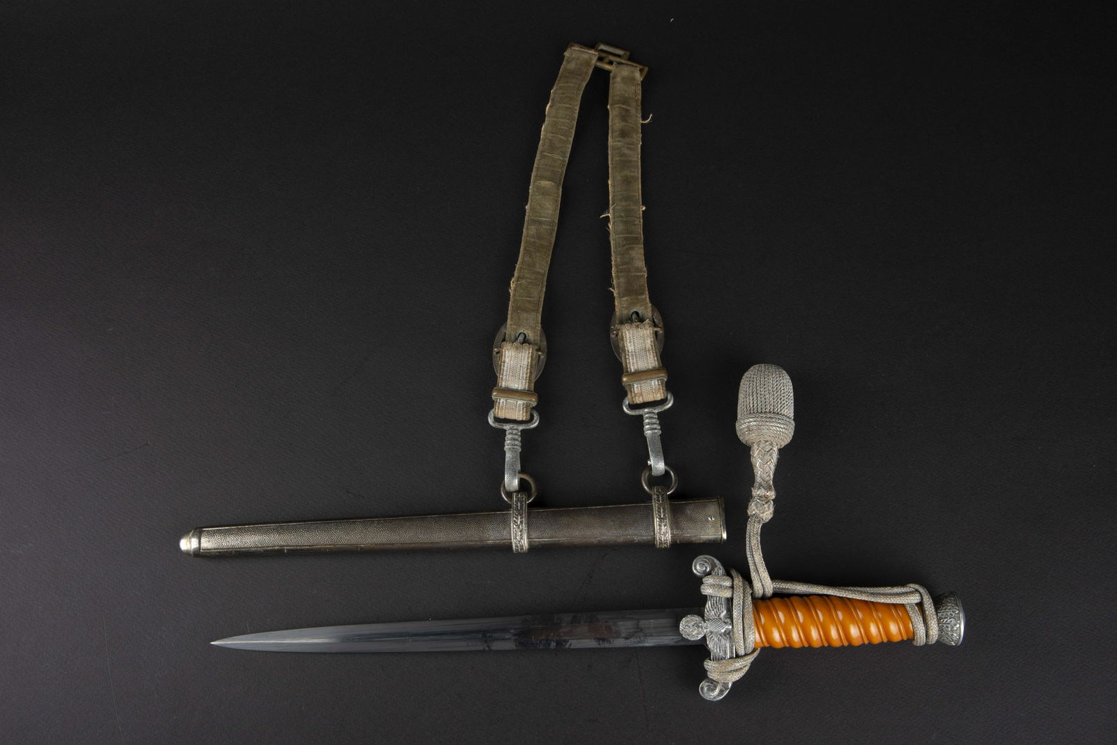 Dague officier Heer. German dagger.: Dague d officier de la Heer. Garnitures en metal, couleur argent. Fusee de couleur orange. Dragonne en fil d argent monte de maniere reglementaire. Fourreau en metal grenele, bagues decorees de feuill