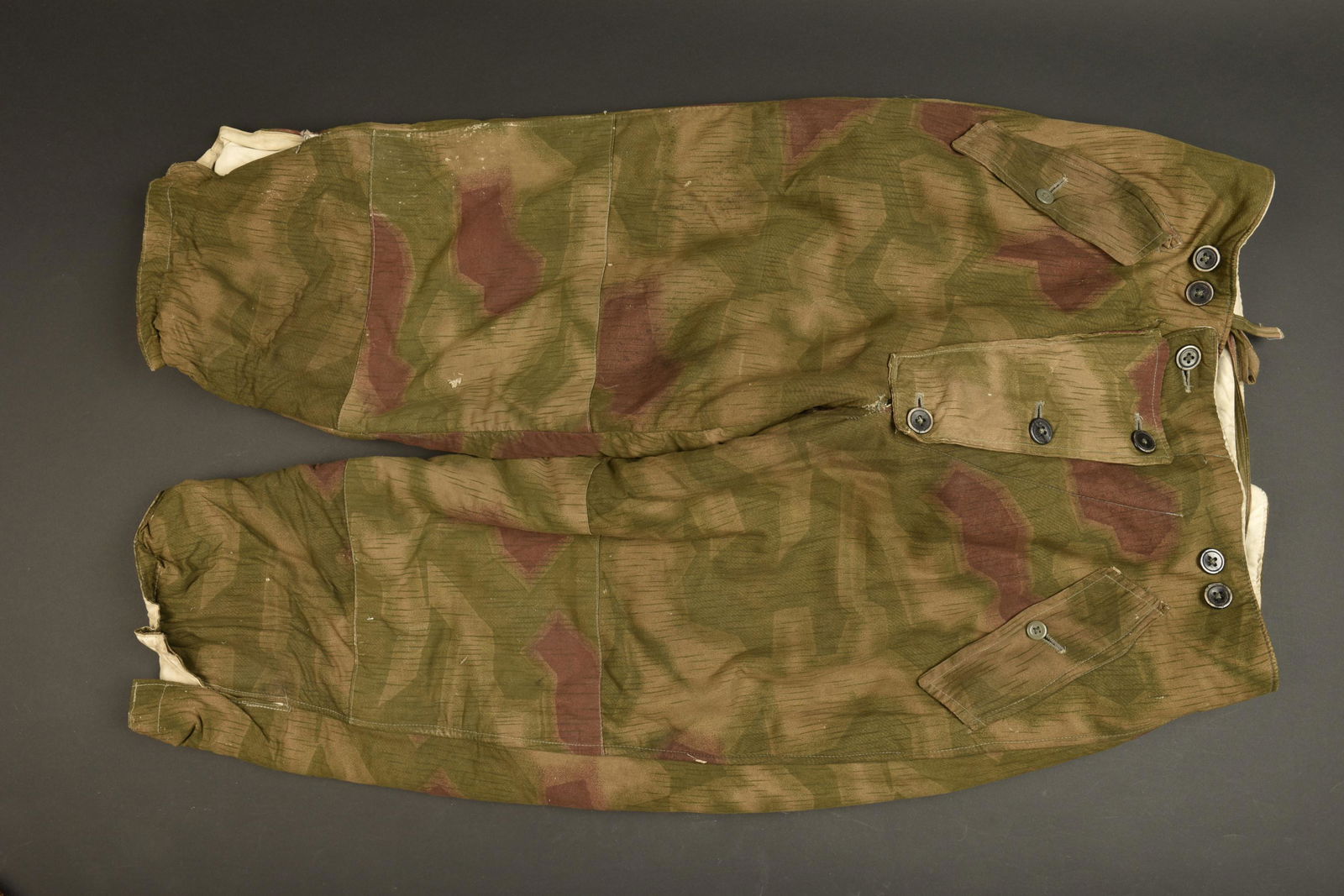 Pantalon camoufle. German camo trousers.: Pantalon camoufle. En tissu camoufle flou, reversible blanc. La majorite des boutons sont presents. Cordon de serrage present. Les bretelles sont manquantes. Certains boutons sont de fabrication civil