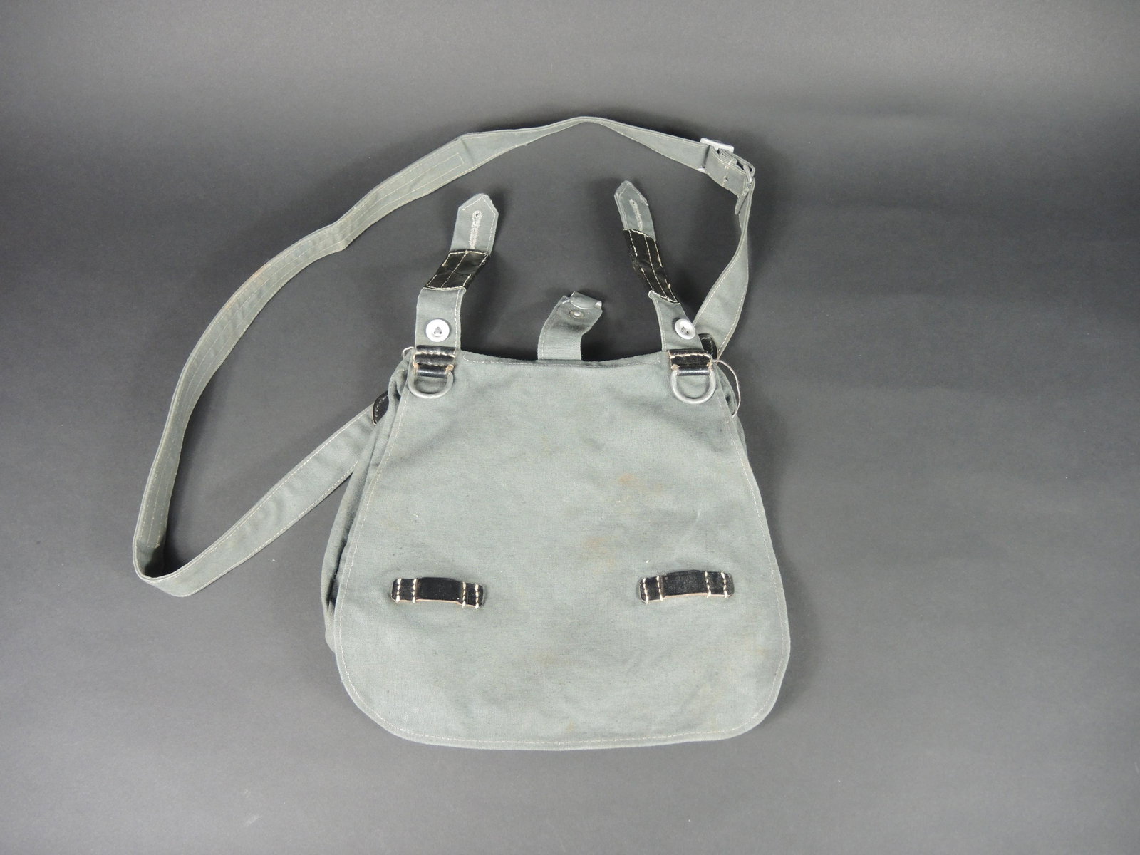 Sac a pain Polizei. Polizei bread bag.: Sac a pain Polizei. En toile gris vert et cuir noir. Sans marquages visibles. Sangle de transport complete. Sans marquages visibles. Ensemble homogene. A noter une legere usure et patine de la piece. 