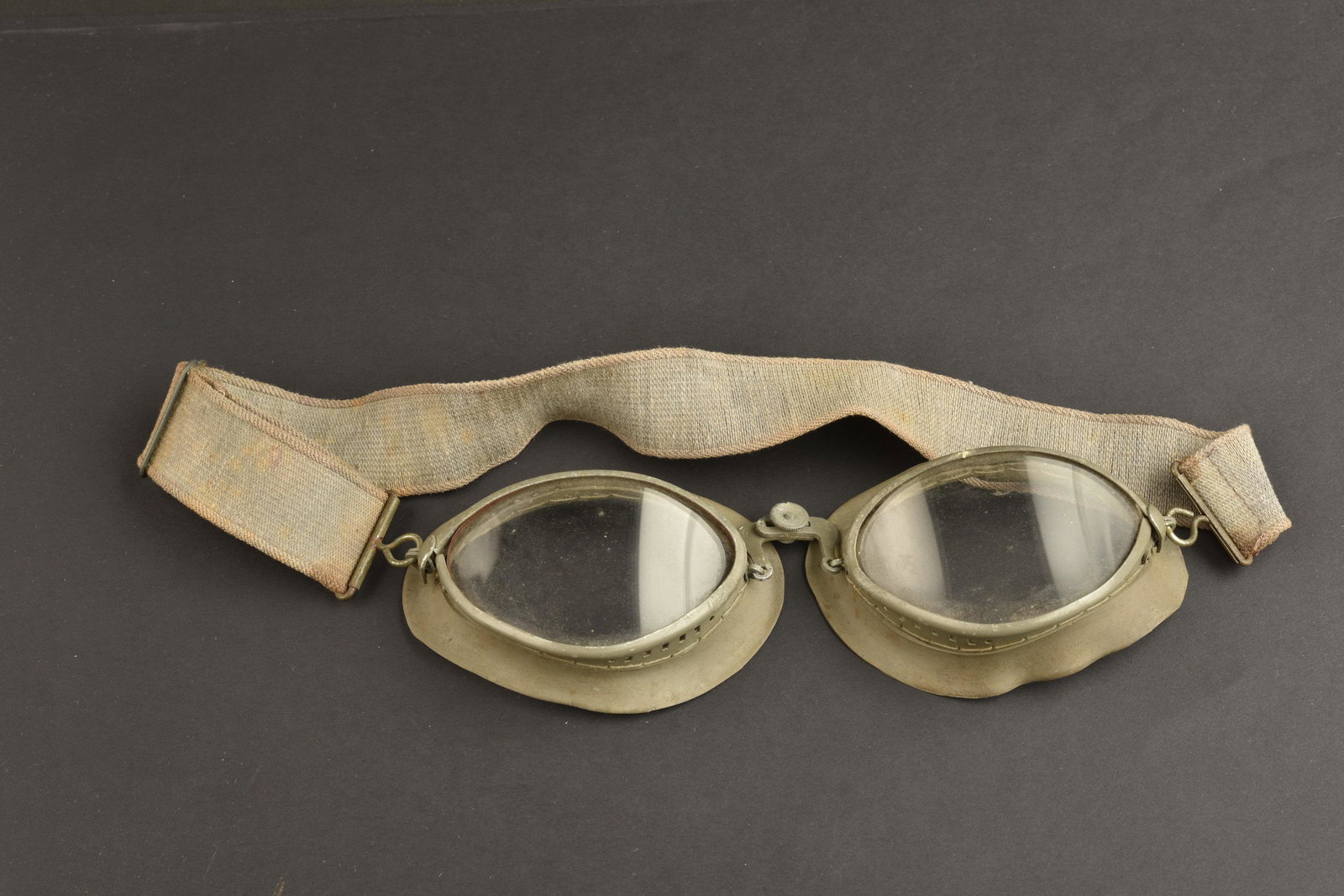 Lunette de motocycliste. Motorcyclist glasses.: Lunettes de motocycliste. Armature en metal, couleur Feldgrau a 90%. Caoutchouc souple. Verres blanc. Elastique souple. Fabrication OW 43. A noter une certaine usure et oxydation de la piece. Collecti