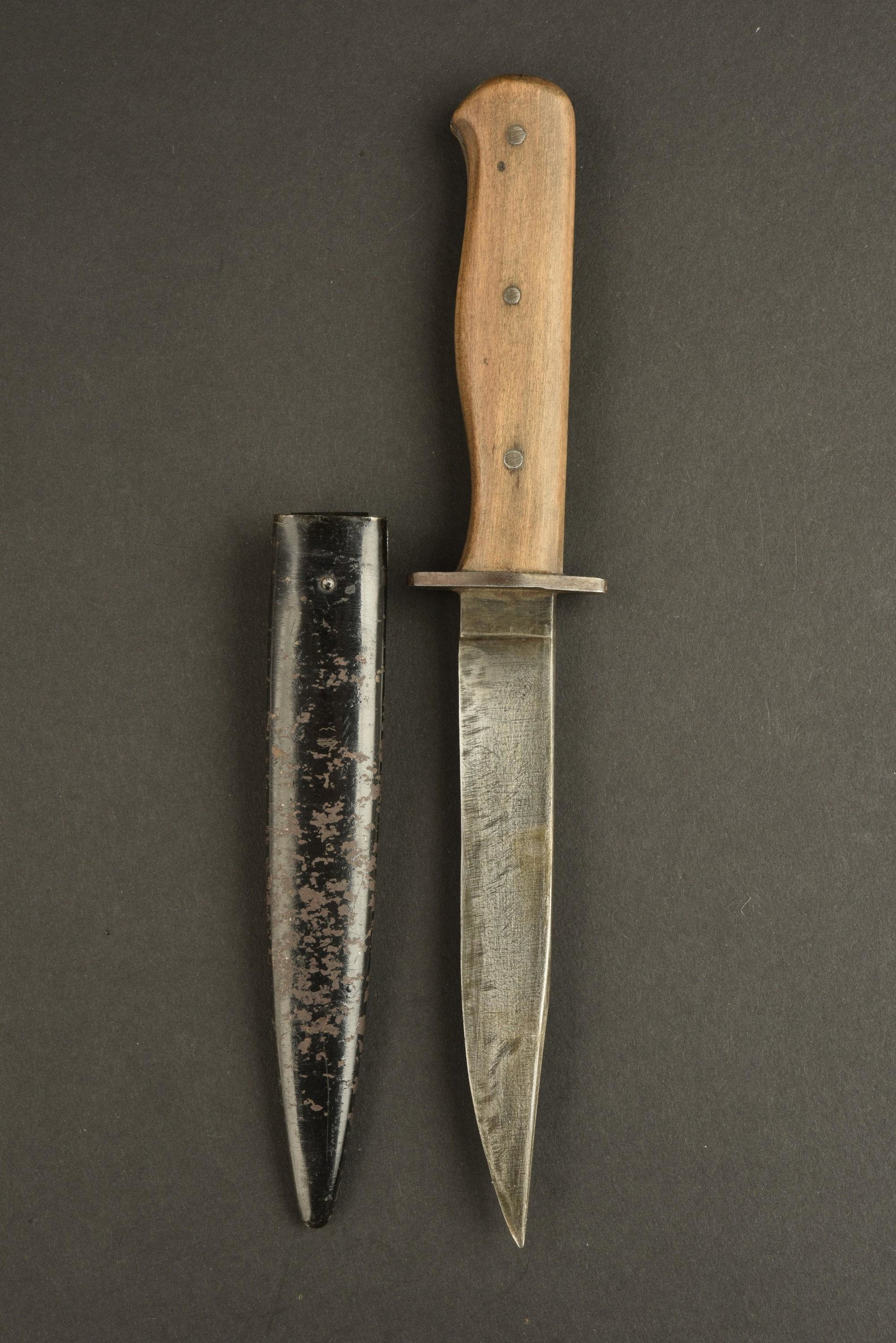 Couteau de botte. Boot knife.: Couteau de botte. Manche en bois, maintenu par trois rivets. Lame affutee, sans marquages visibles. Fourreau en metal, peinture noire a 60%. Attache complete. A noter une certaine usure et patine de l