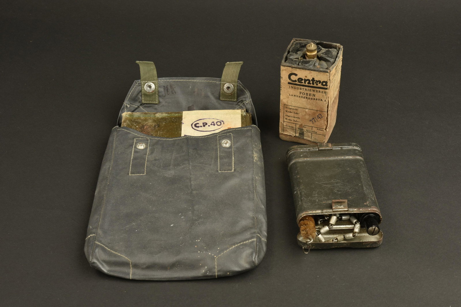 Equipement allemand. German Equipment: Equipement allemand. Comprenant une pile pour telephone, etiquette presente mais abimee, partie en bakelite fendue et cassee avec des manques. Fabrication Centra, datee 1942. Une housse de gasplane en