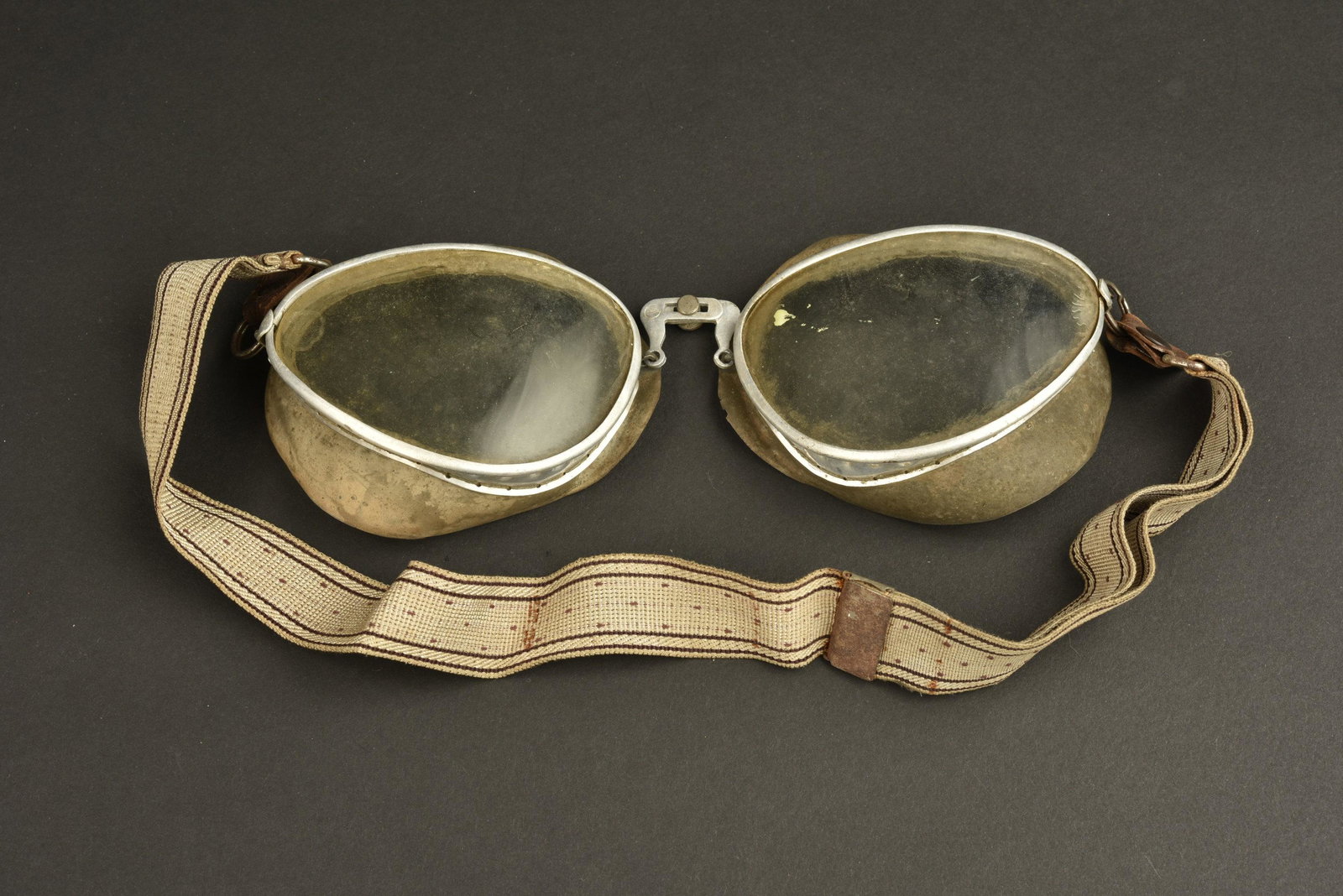Lunette de motocycliste. Motorcyclist glasses.: Lunettes de motocycliste. Armature en metal. Caoutchouc souple. Verres blanc. Elastique distendu. Fabrication Mima, sans date visible. A noter une certaine usure et oxydation de la piece. Etat II+. Mo
