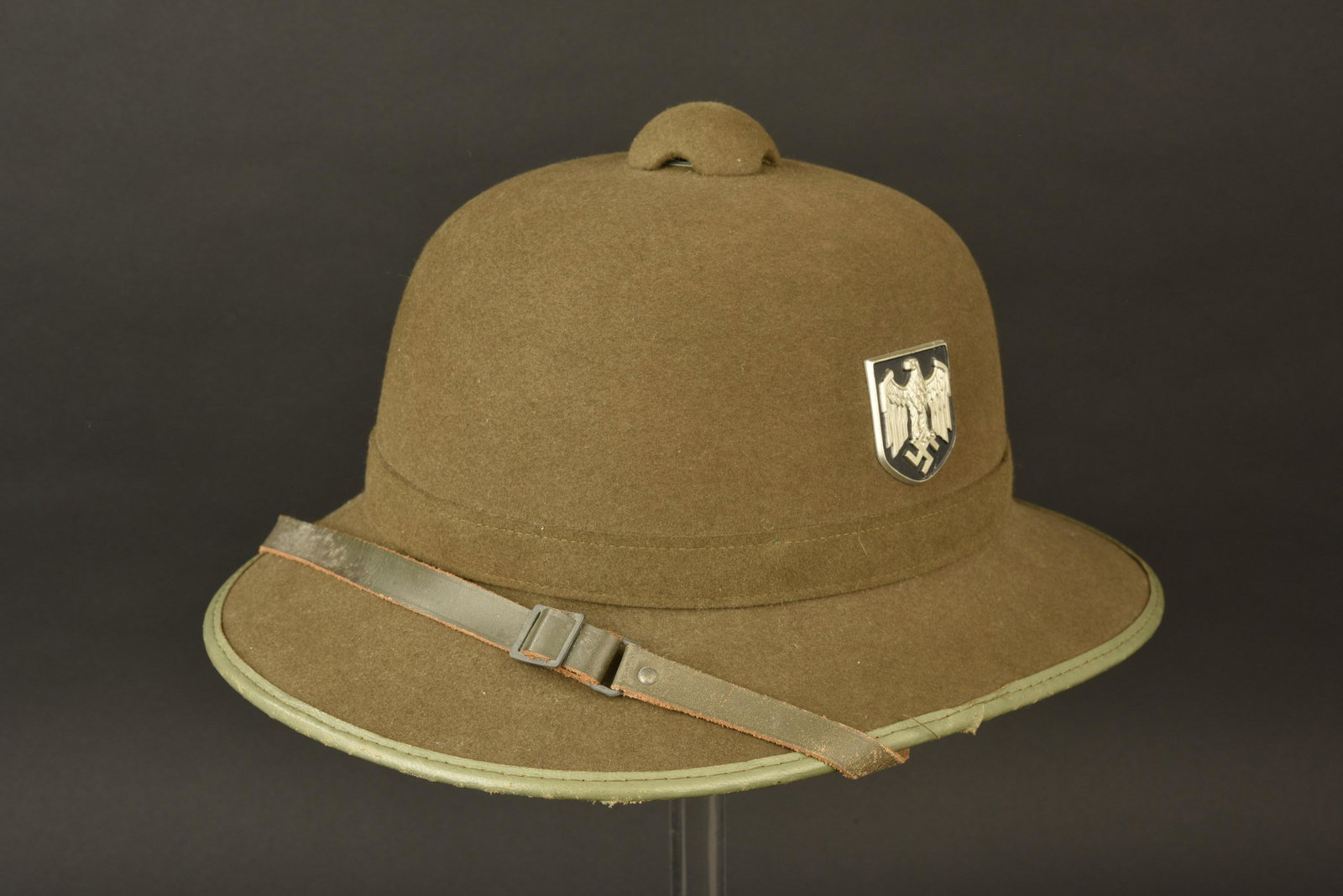 Casque tropical Heer. Heer tropical helmet.: Casque tropical Heer. Second modele. En feutrine Feldgrau et cuir vert. Insignes metalliques presents. Les insignes n ont pas ete demontes, afin de verifier les pattes de fixation. Jugulaire en cuir c