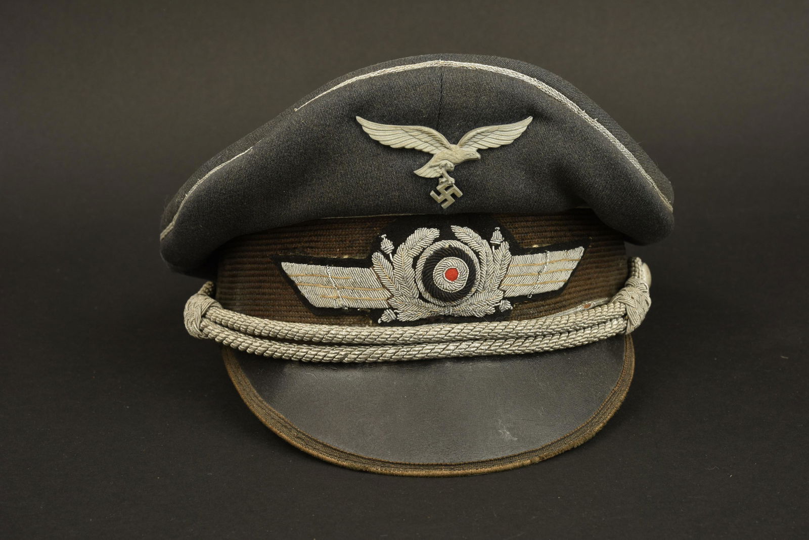 Casquette LW. Luftwaffe cap: Casquette de la Luftwaffe. Modele pour aspirant de la Luftwaffe. En gabardine gris/bleu. Triple lisere argent faisant le tour de la coiffure. Bandeau en mohair fortement decolore. Cocarde et feuilles