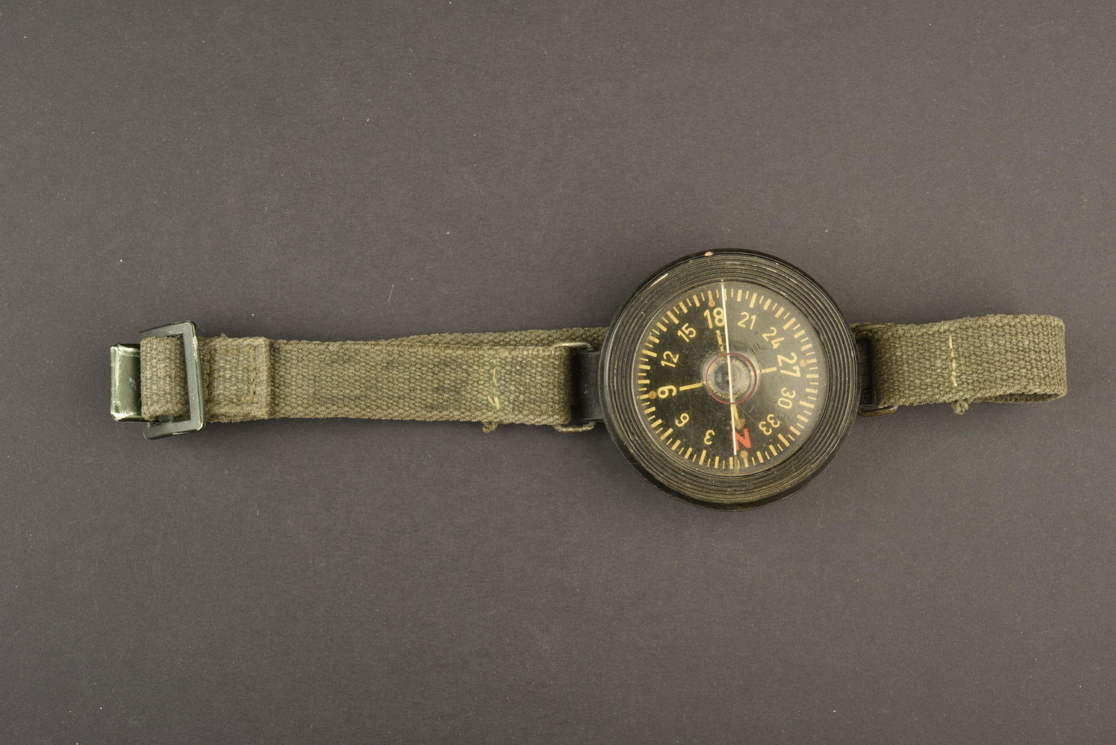 Boussole de poignee. Handle compass.: Boussole de poignee. Bracelet toile posterieur. Boussole en bakelite ,noire, fond noir. Fond blanc. Fonctionnelle. Marquages AK 39 au dos. A noter une certaine usure et patine de la piece. Etat II+. H