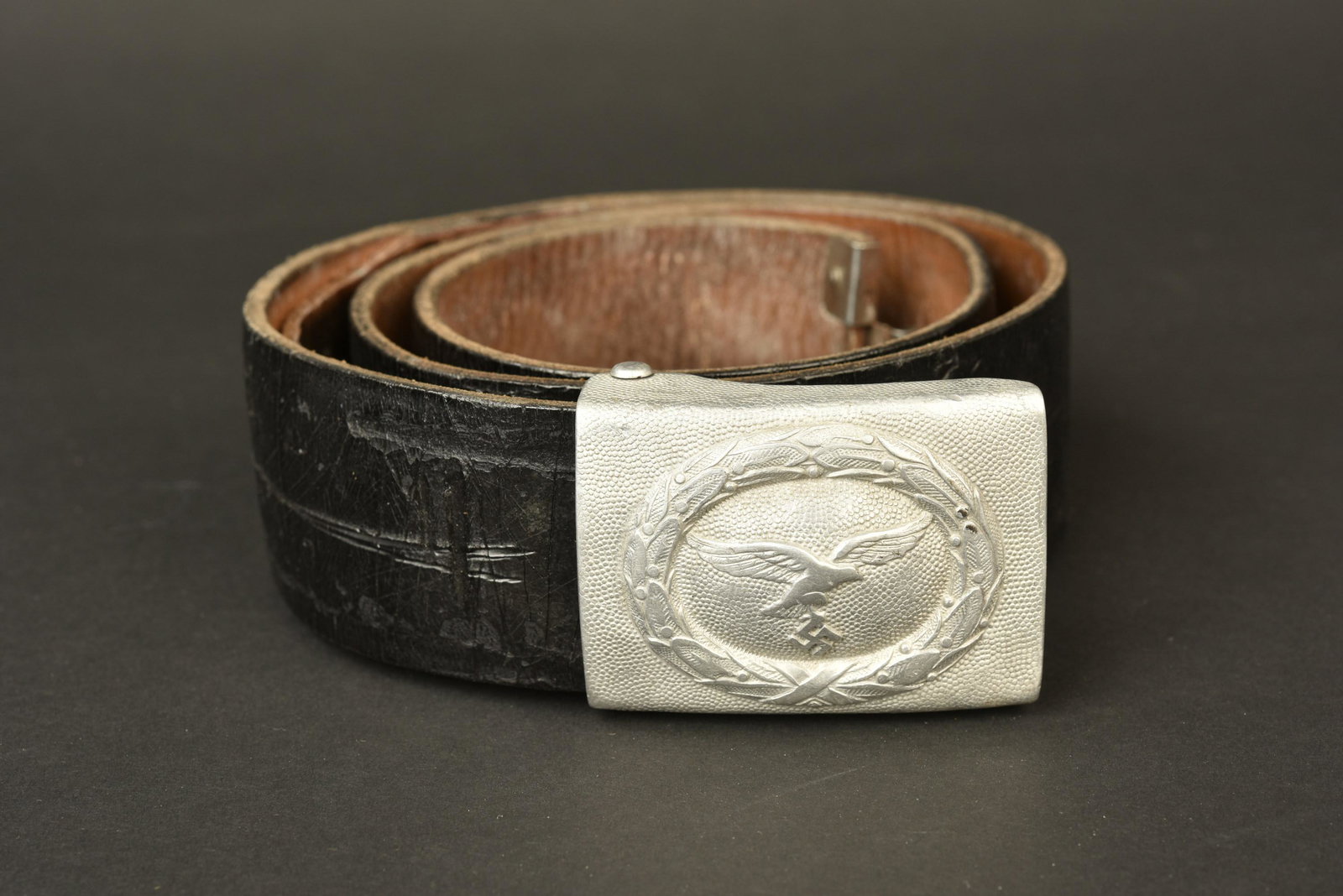 Ceinturon Luftwaffe. Luftwaffe belt: Ceinturon Luftwaffe. En cuir noir, taille 88, sans marquages visibles, bouclerie en metal nickele. Patte de reglage complete. Boucle de ceinturon en aluminium grenele, usee et presentant quelques boss