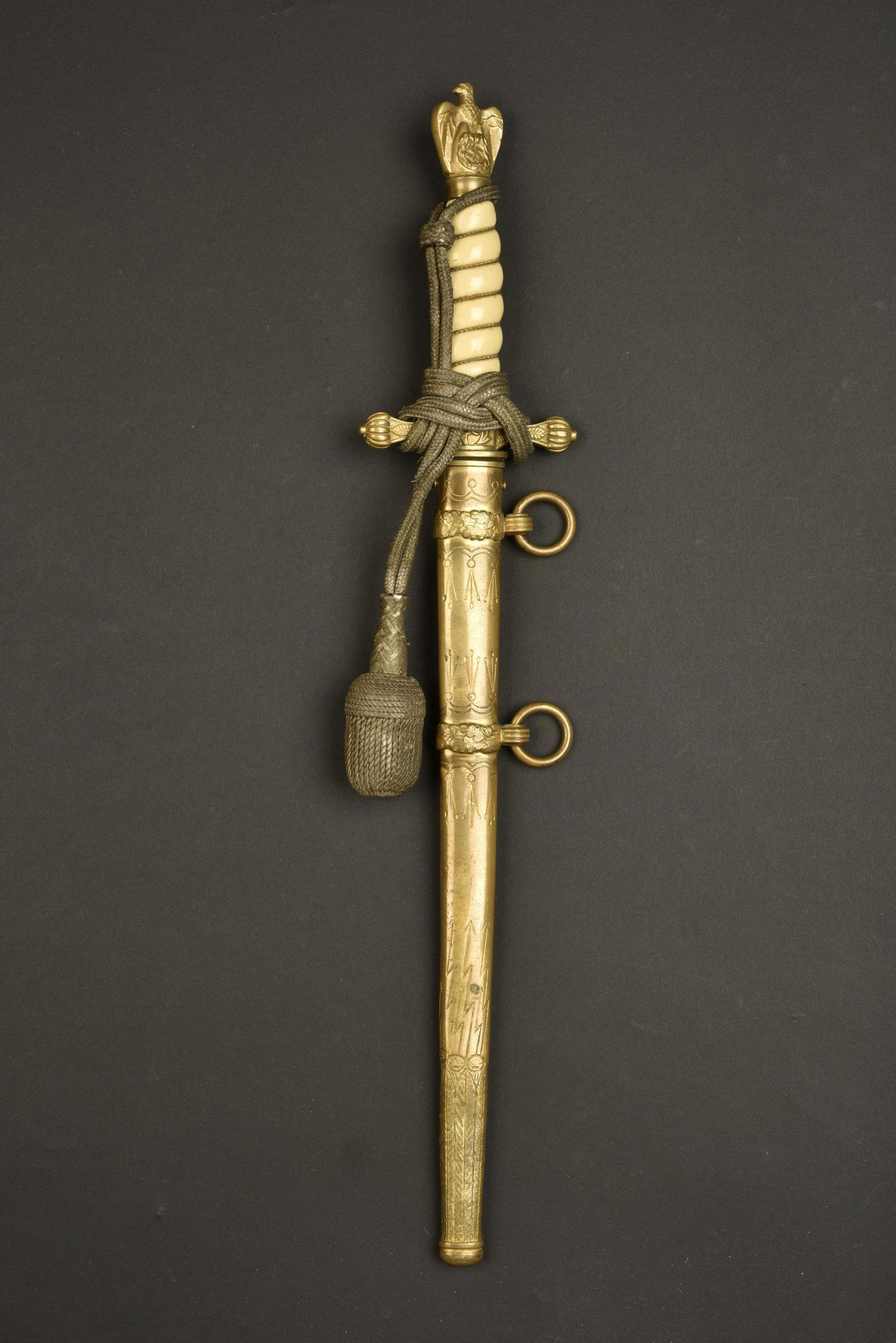 Dague Kriegsmarine. Kriegsmarine dagger: Dague Kriegsmarine. Pommeau representant un aigle aux ailes repliees. Manche en celluloid blanche. Dragonne nouee de maniere reglementaire. Bouton poussoir fonctionnel. Lame gravee d une ancre de mari