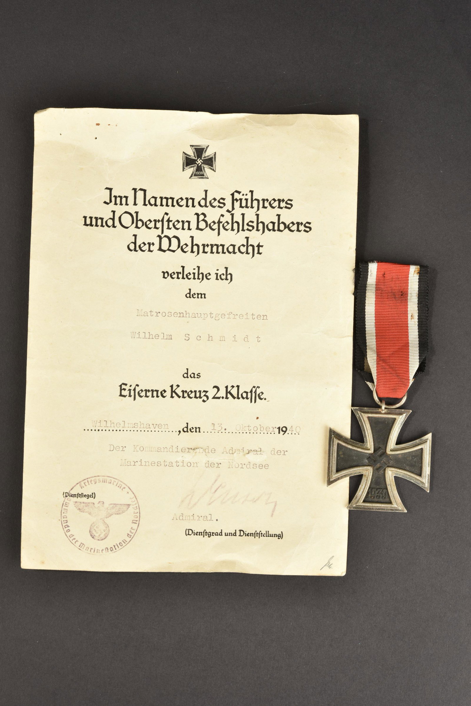 Croix de fer 2nd classe. EkII: Croix de fer 2nd classe. Fabrication en trois parties, ruban present, code fabricant 65. Diplome en papier, attribue au Matrosenhauptgefreiten Wilhelm Schmidt, a Wilhelmshaven le 13 octobre 1940. A no