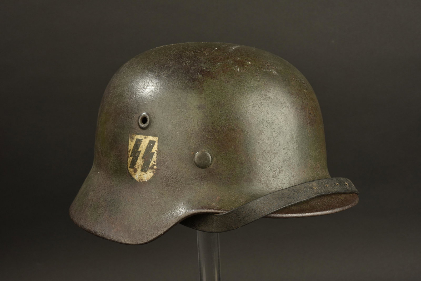 Casque SS. SS helmet: Casque SS. Coque de casque M40. Fabrication ET62, numero de lot illisible. Interieur de la coque fortement oxyde. Coiffe en cuir complete, une couture est defaite. Cuir sec et cassant. Cordon de serra