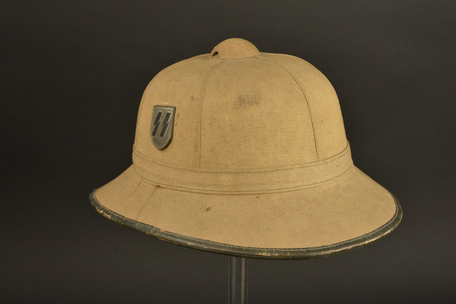 Casque tropical SS. SS tropical helmet: Casque tropical SS. En forte toile sable. Bordure en cuir. Insignes SS et couleurs nationales, ils n ont pas ete demontes afin de verifier les pattes de fixation. Jugulaire manquante. Interieur double