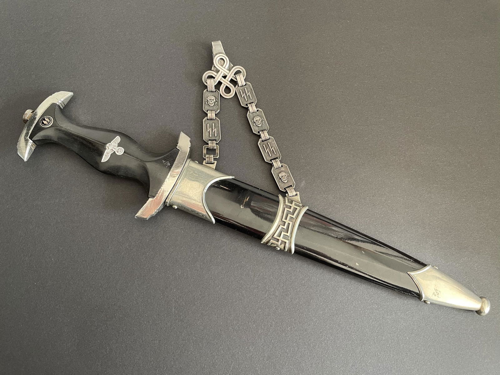 Dague 36 SS. SS dagger: Dague dâ€™officier de la SS du modele 1936. Fourreau en maillechort de fabrication precoce comportant une double beliere en acier nickele dont les deux derniers anneaux plats sont rectangulaires,