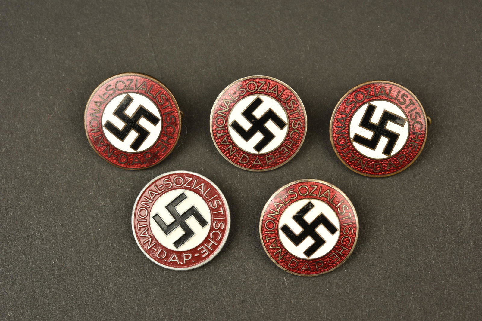 Insignes DAP. DAP insignia: Insignes DAP. Quatre insignes en metal emaille et un insigne peint, marques Nationalsozialistische DAP. Toutes les attaches sont presentes. Fabrication RZM M1/72, correspondant a Fritz Zimmermann, Stu