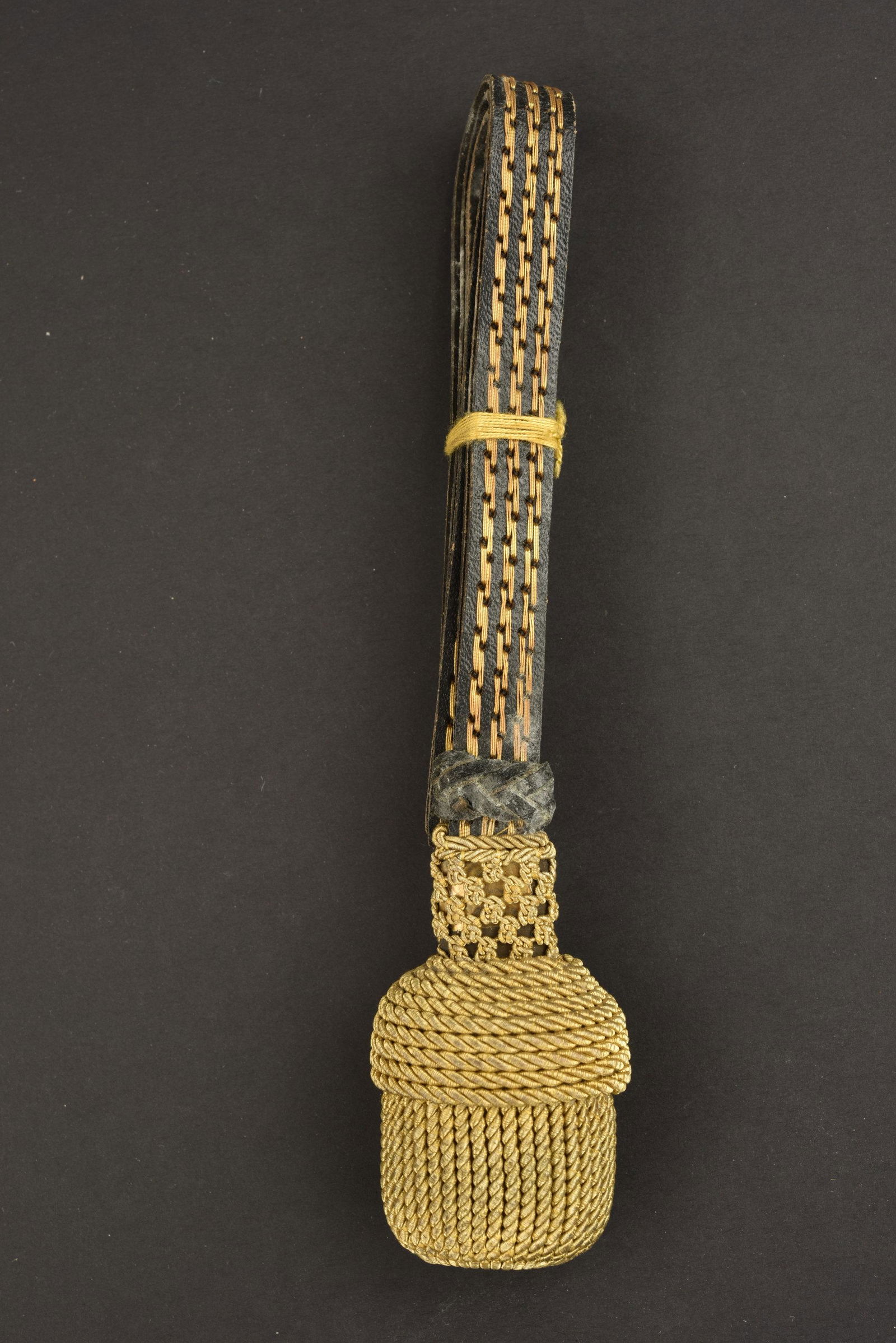 Dragonne sabre Bergbau. Bergbau sword strap.: Dragonne sabre Bergbau. Laniere en cuir noir, surpique de fils dores. Gland completement dore. Pliee d'origine, jamais utilisee. A noter une certaine usure et patine de la piece. Etat II+. Bergbau swo