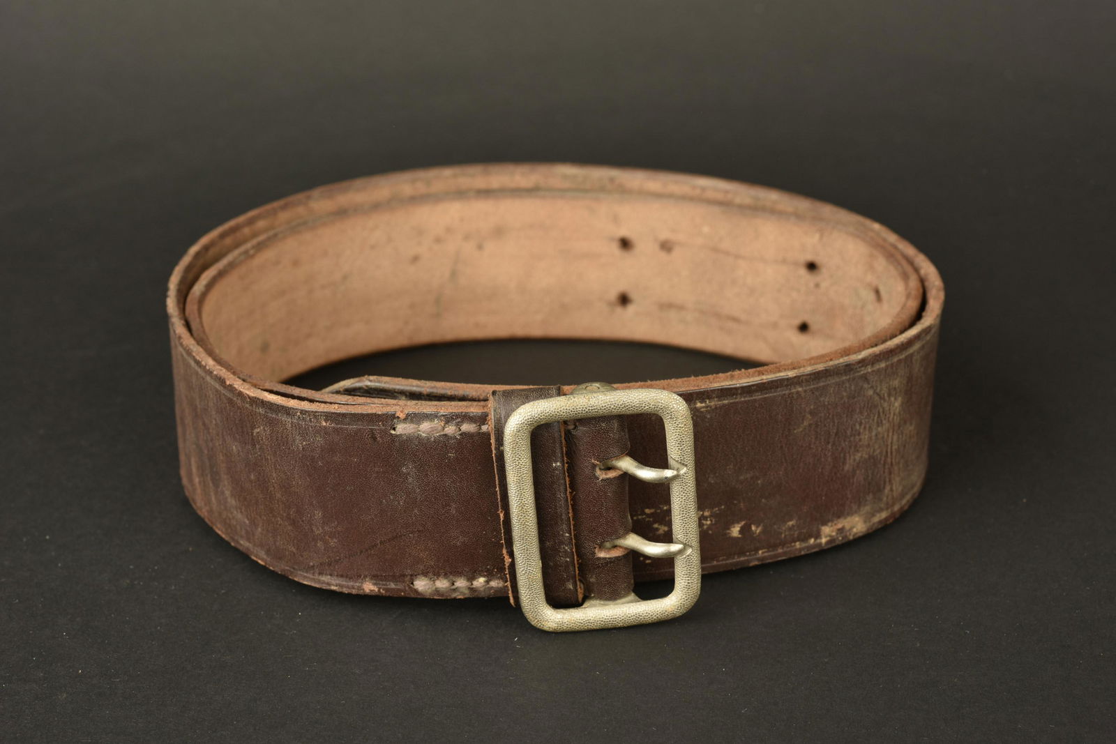 Ceinturon RZM. RZM belt: Ceinturon RZM. En cuir marron. Boucle a deux ardillons, en metal grenele. Marquages RZM L2/748/40. A noter une certaine usure et patine de la piece. Etat II+. RZM belt. In brown leather. Buckle with t