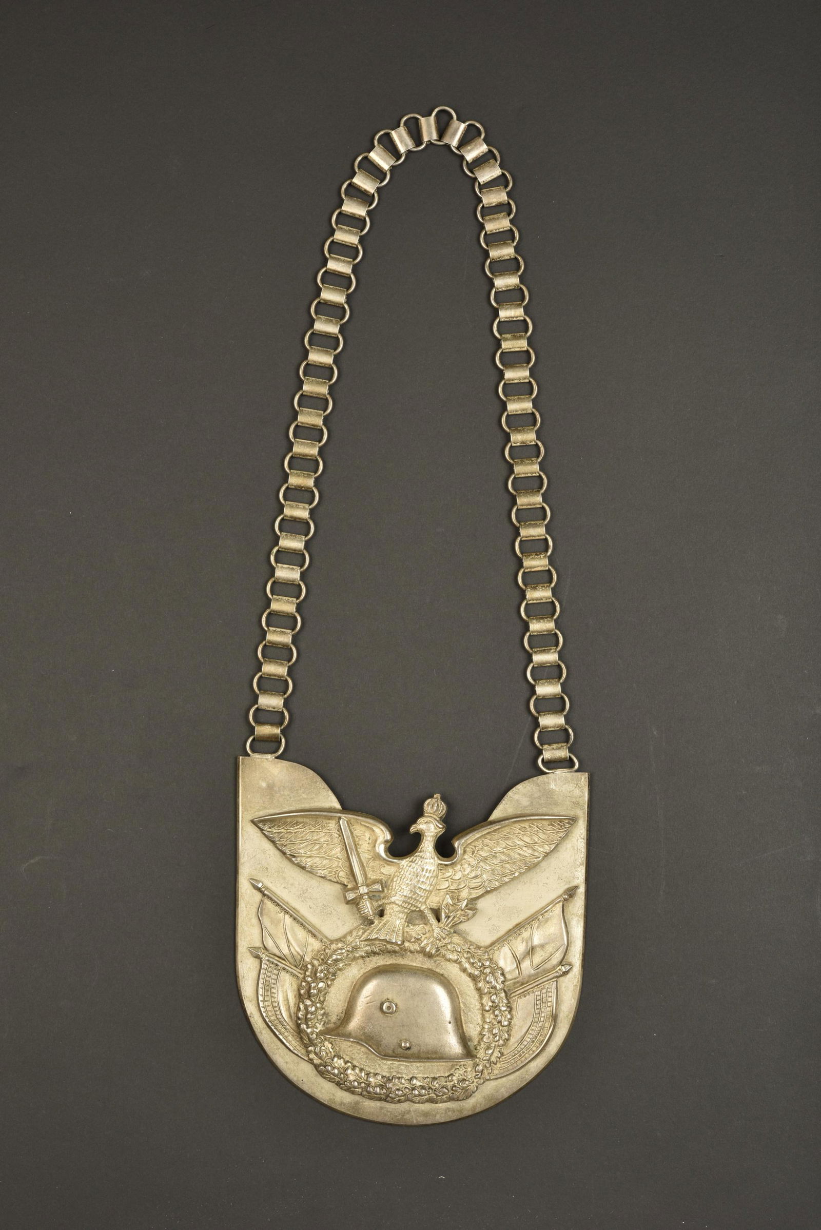 Hausse col Der Stalhelm. Der Stamhelm gorget: Hausse col Der Stalhelm. En epais metal, couleur argent. Decors en relief. Chainette presente a anneaux mobiles. Dos recouvert ne disposant pas de doublure en drap. Sans marquages visibles. Couleur ar