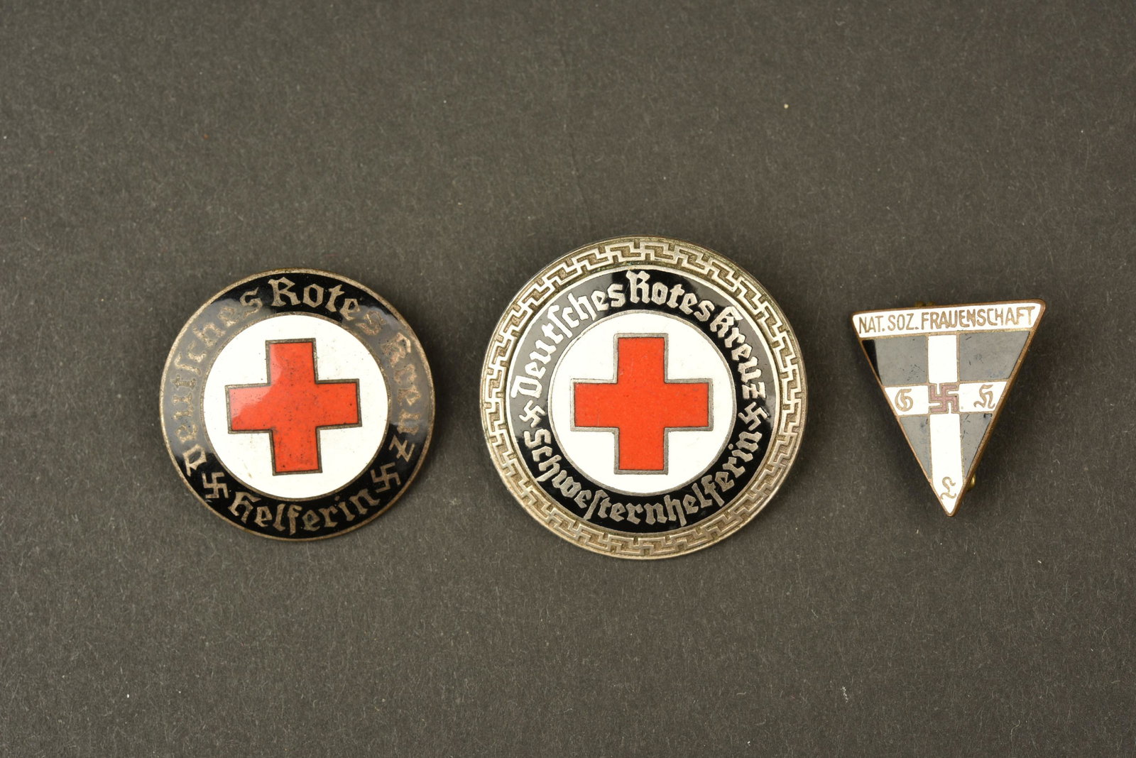 Insignes DRK. DRK insignia: Insignes DRK. Comprenant un insigne Deutsches Rotes Kreuz Schwersternhelferin. Attache complete mais tordue, marquee Ges Gesch. Un insigne en metal emaille Nat Soz Frauenschaft, attache complete, fabr