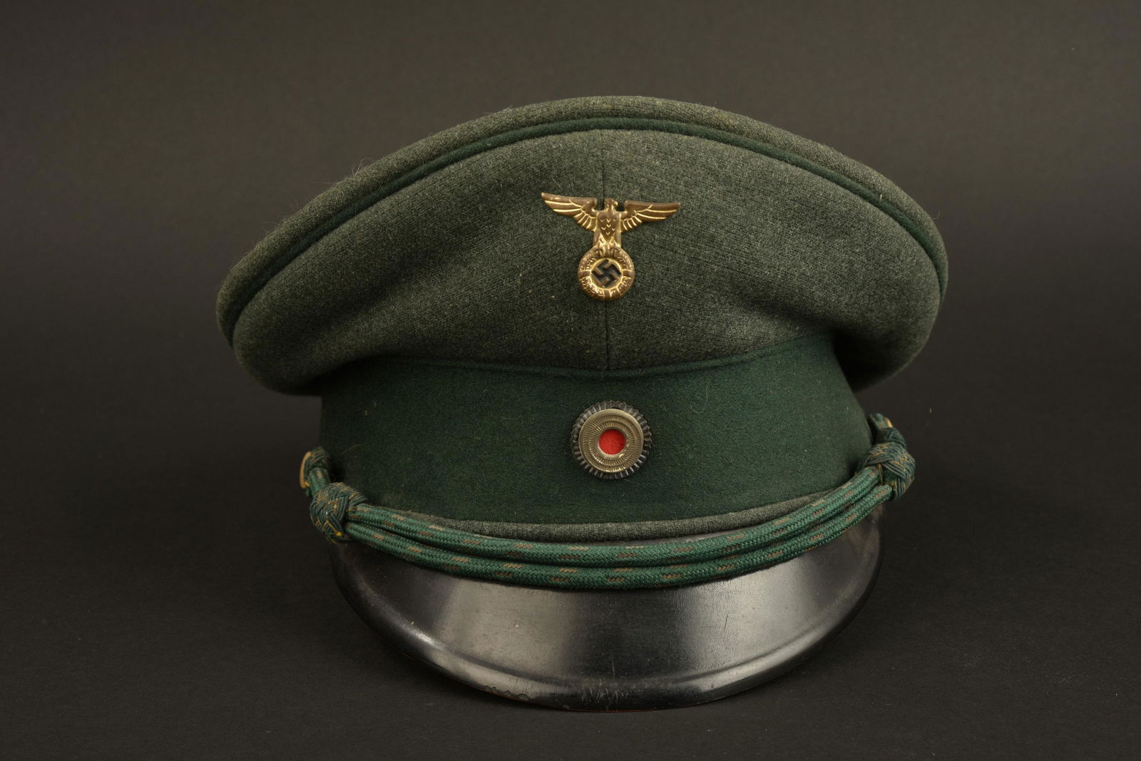 Casquette de forestier. Forester's cap: Casquette de forestier. En drap Feldgrau, lisere vert fonce. Bandeau en Drap vert Fonce. Insignes metalliques. Les insignes n'ont pas ete demonte afin de verifier les pattes de fixation. Fausse jugula