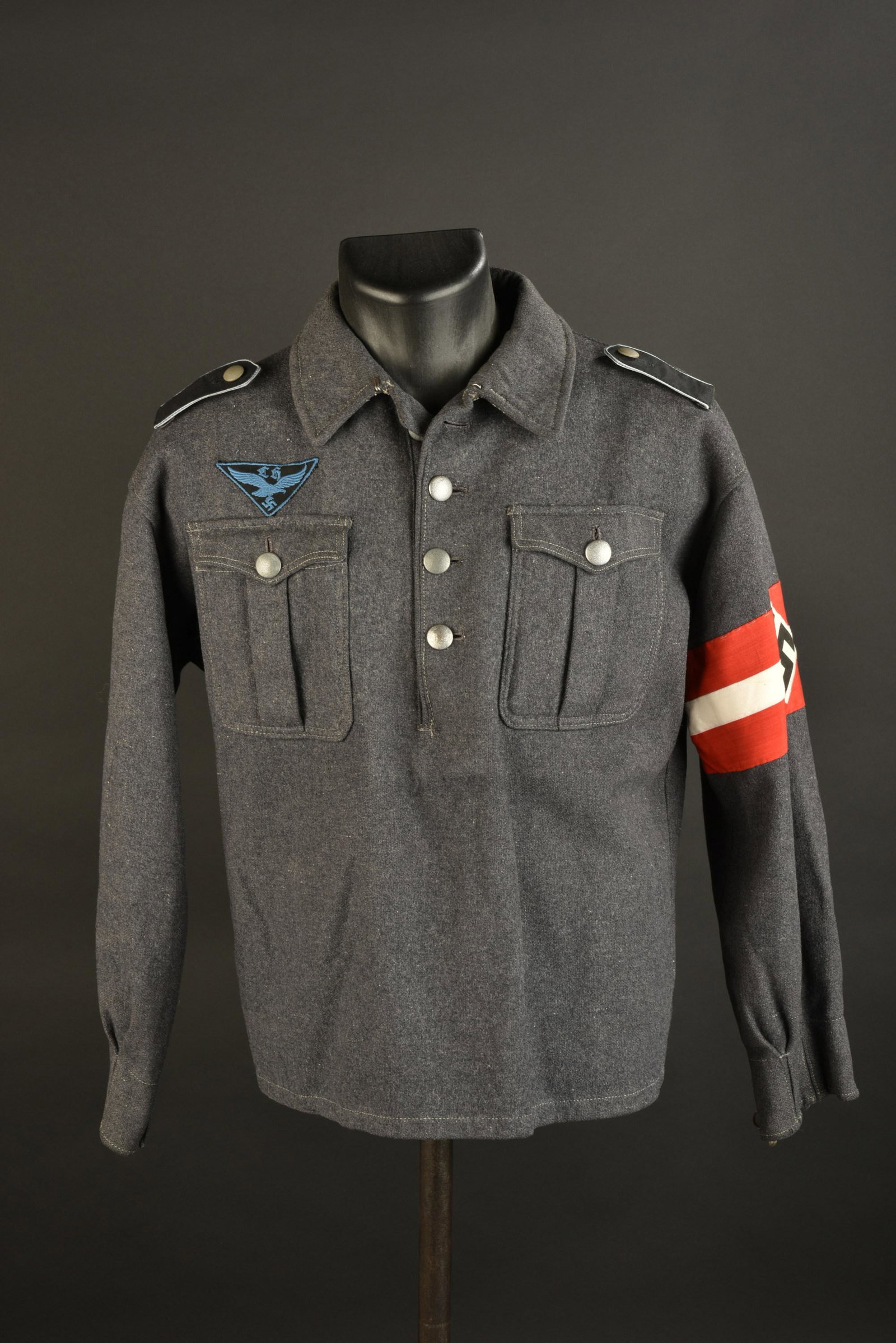 Blouson HJ Luftwaffe. Hitlerjugend jacket: Blouson Hitlerjugend Luftwaffe. En drap gris bleu. Tous les boutons sont presents. Pattes d'epaule troupe, lisere bleu ciel. Insigne de poitrine brode et monte main. Brassard en tissu coton imprime, i