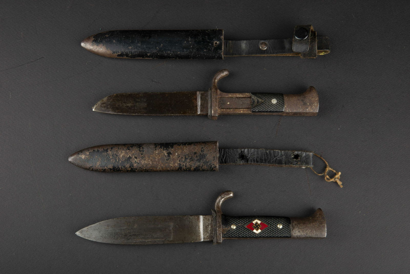 Couteaux de marche HJ. Hitlerjugend daggers: Couteaux de marche Hitlerjugend. Comprenant un couteau, partie metallique oxydee. Plaquettes cassees, insigne manquant. Fourreau present, repeint, modele posterieur, lame raccourcie et oxydee, fabrica