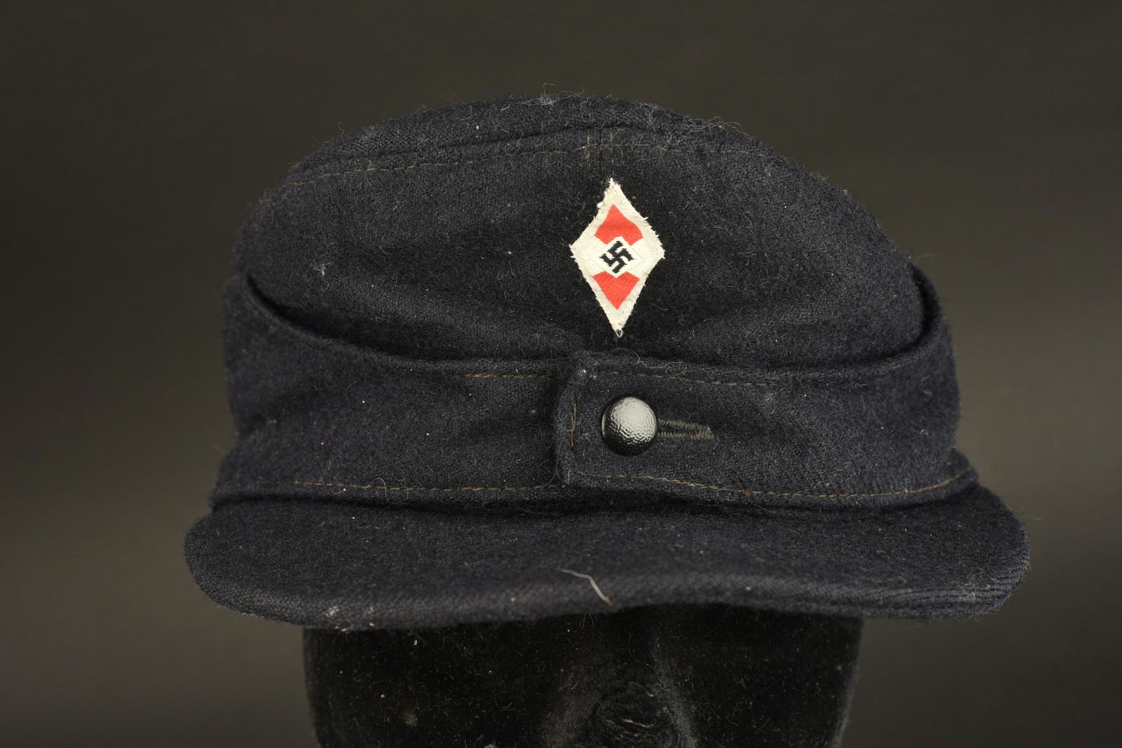 Feldmutze HJ. Hitlerjugend cap: Feldmutze Hitlerjugend. En drap noir, bouton en metal fermant les rabats. Insigne HJ tisse monte main. Interieur double d'une satinette noir. Etiquette RZM numero 421727, code fabricant 240. Bandeau d